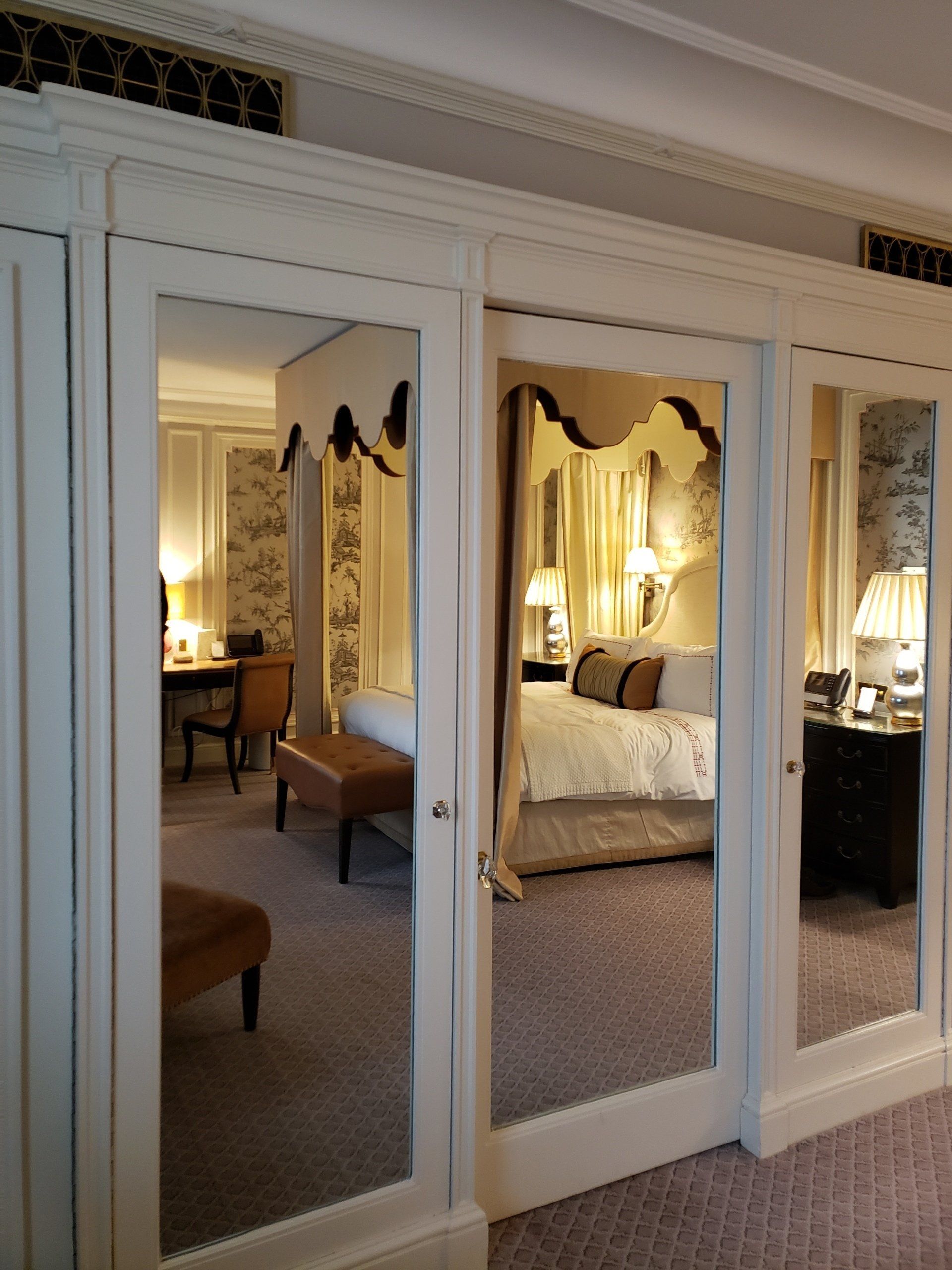 A bedroom with a canopy bed and mirrored doors