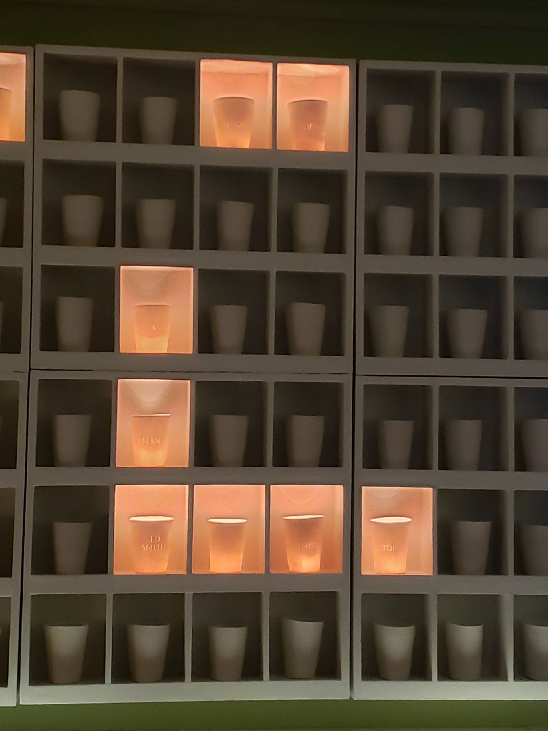 A wall of shelves filled with lots of cups and candles.