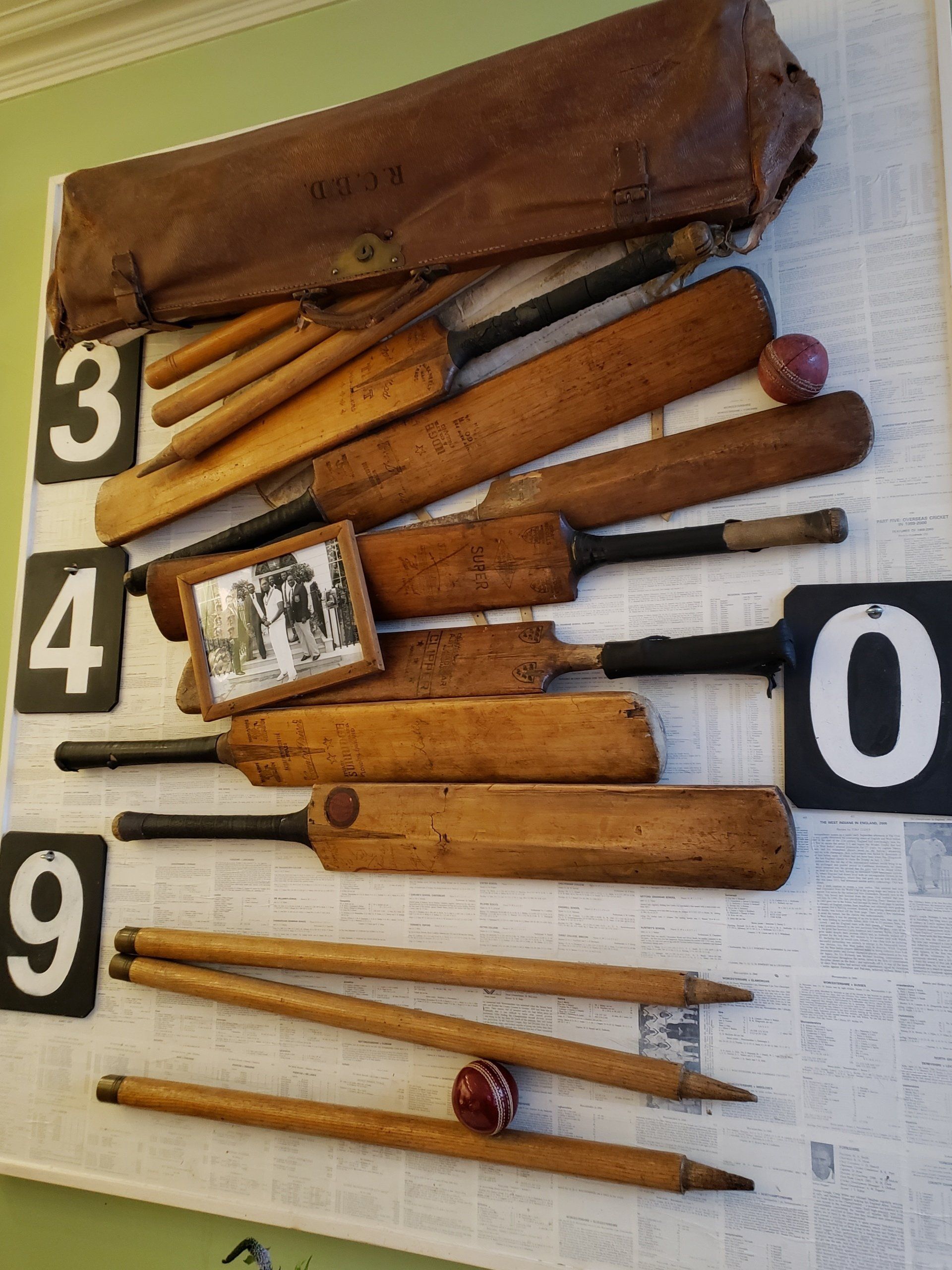 A bunch of wooden cricket bats hanging on a wall