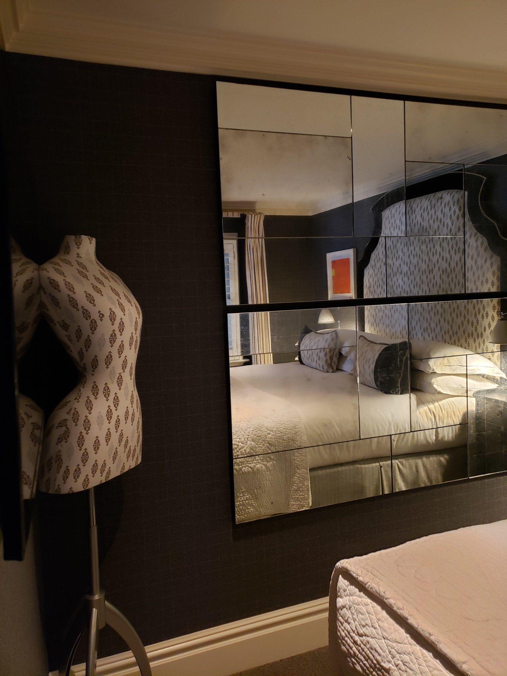 A bedroom with a large mirror and a mannequin