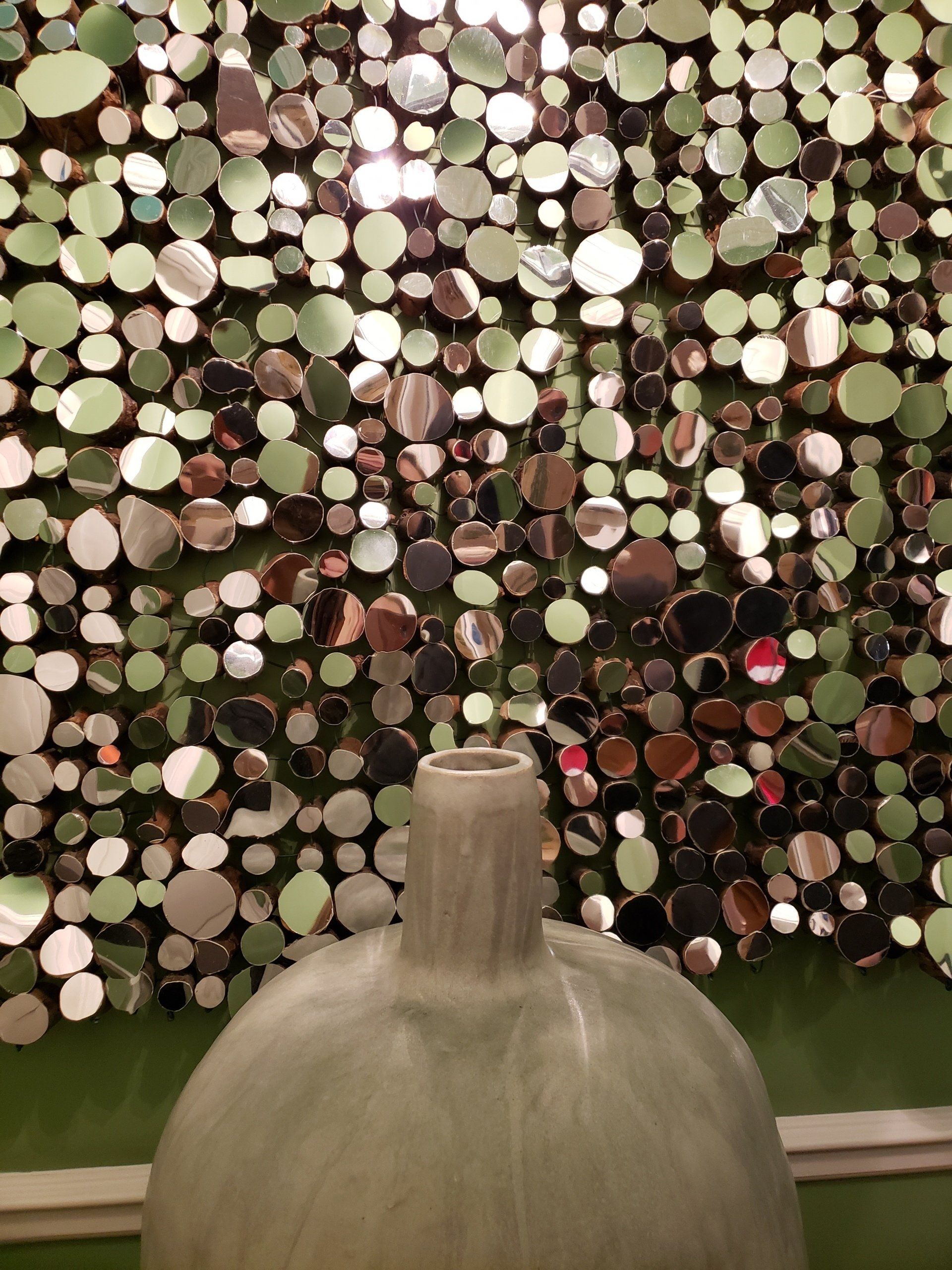 A vase is sitting in front of a wall of mirrors