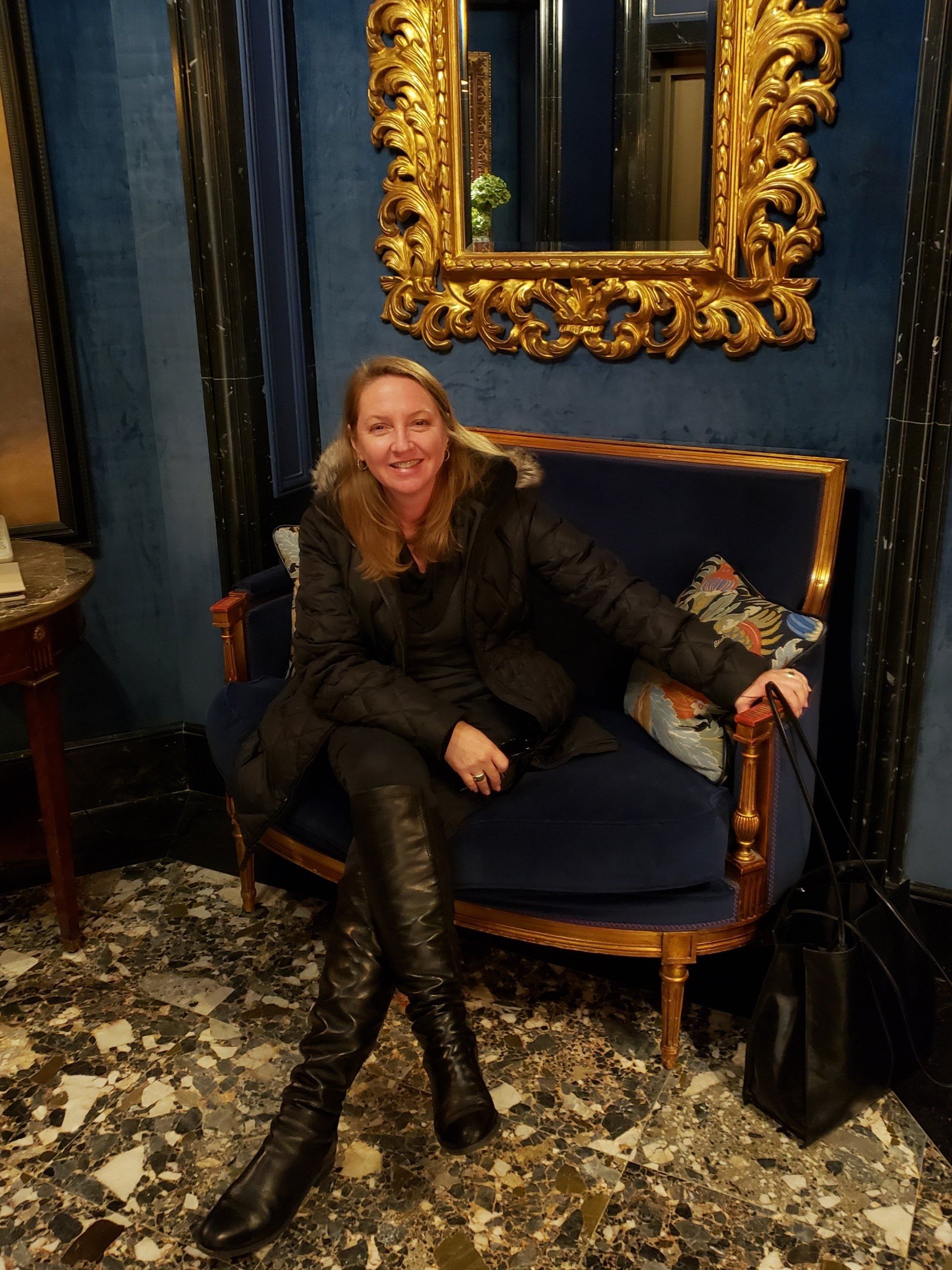 A woman is sitting on a blue couch in front of a mirror