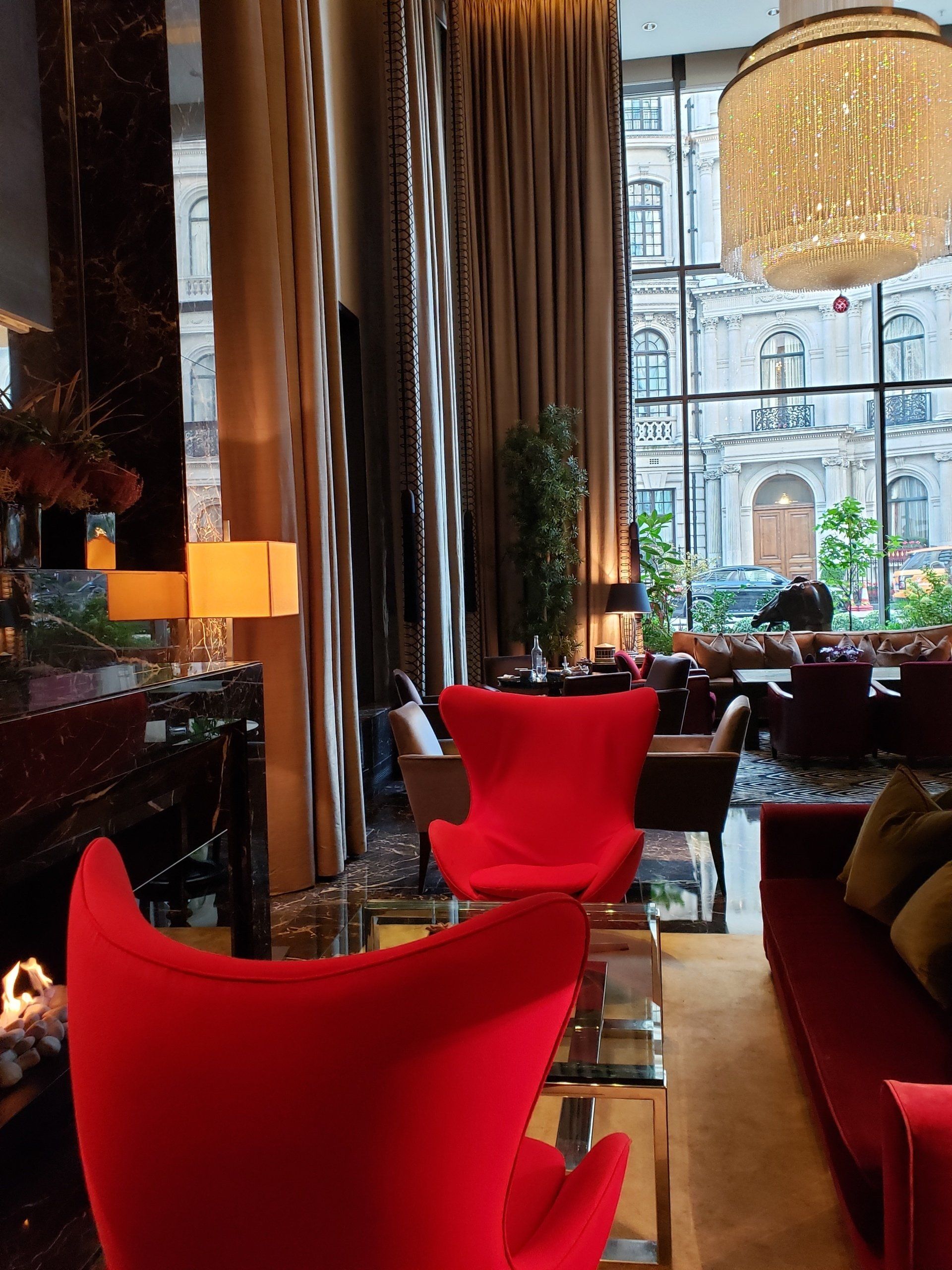 A living room with red chairs and a chandelier