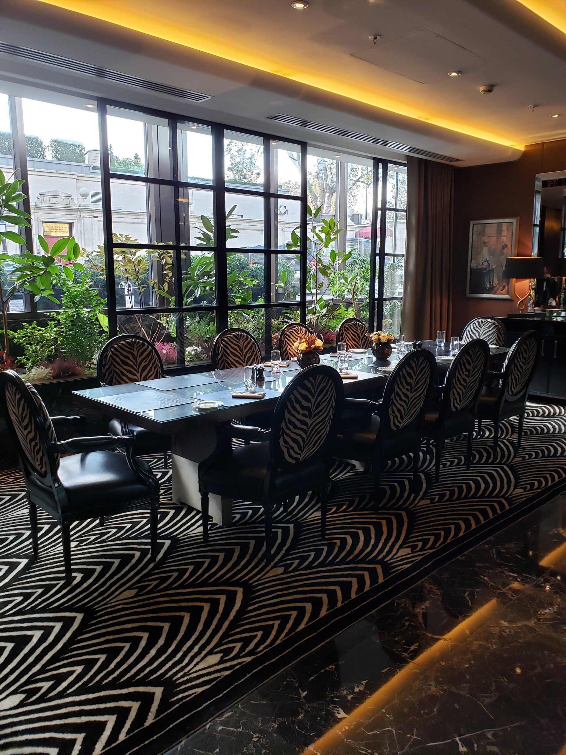 A dining room with a table and chairs and a large window.