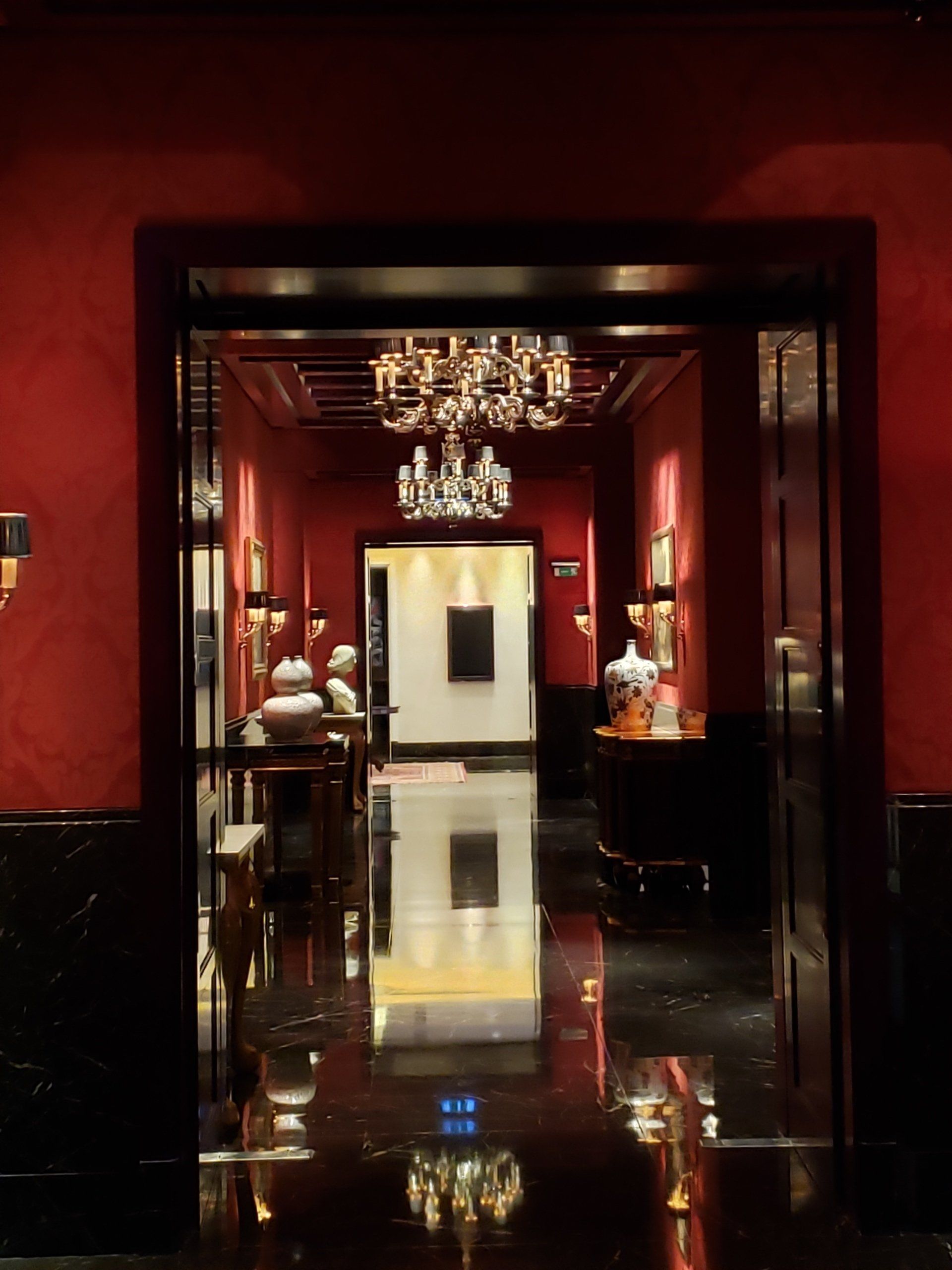 A hallway with red walls and a chandelier hanging from the ceiling