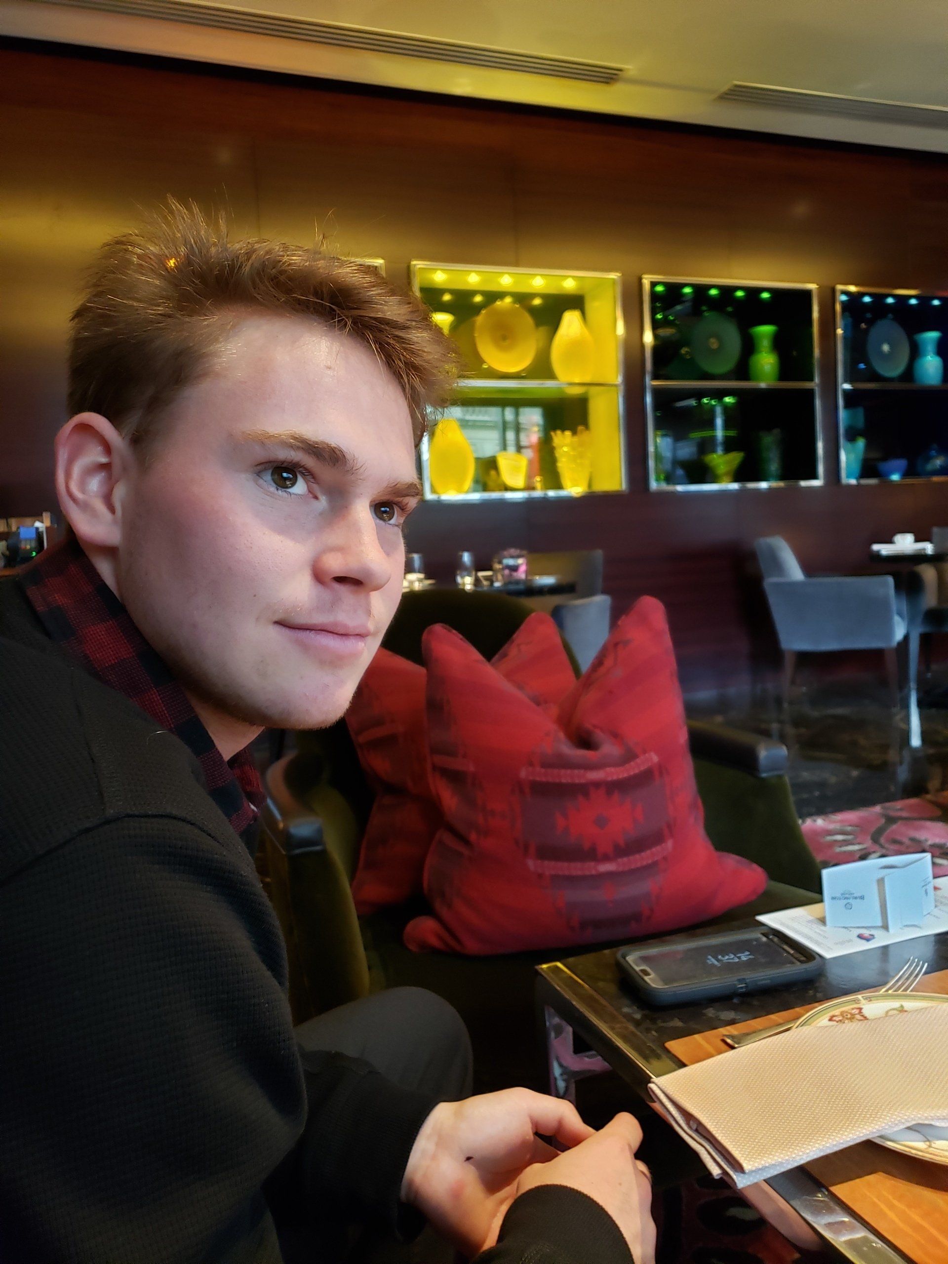 A young man is sitting at a table with a red pillow
