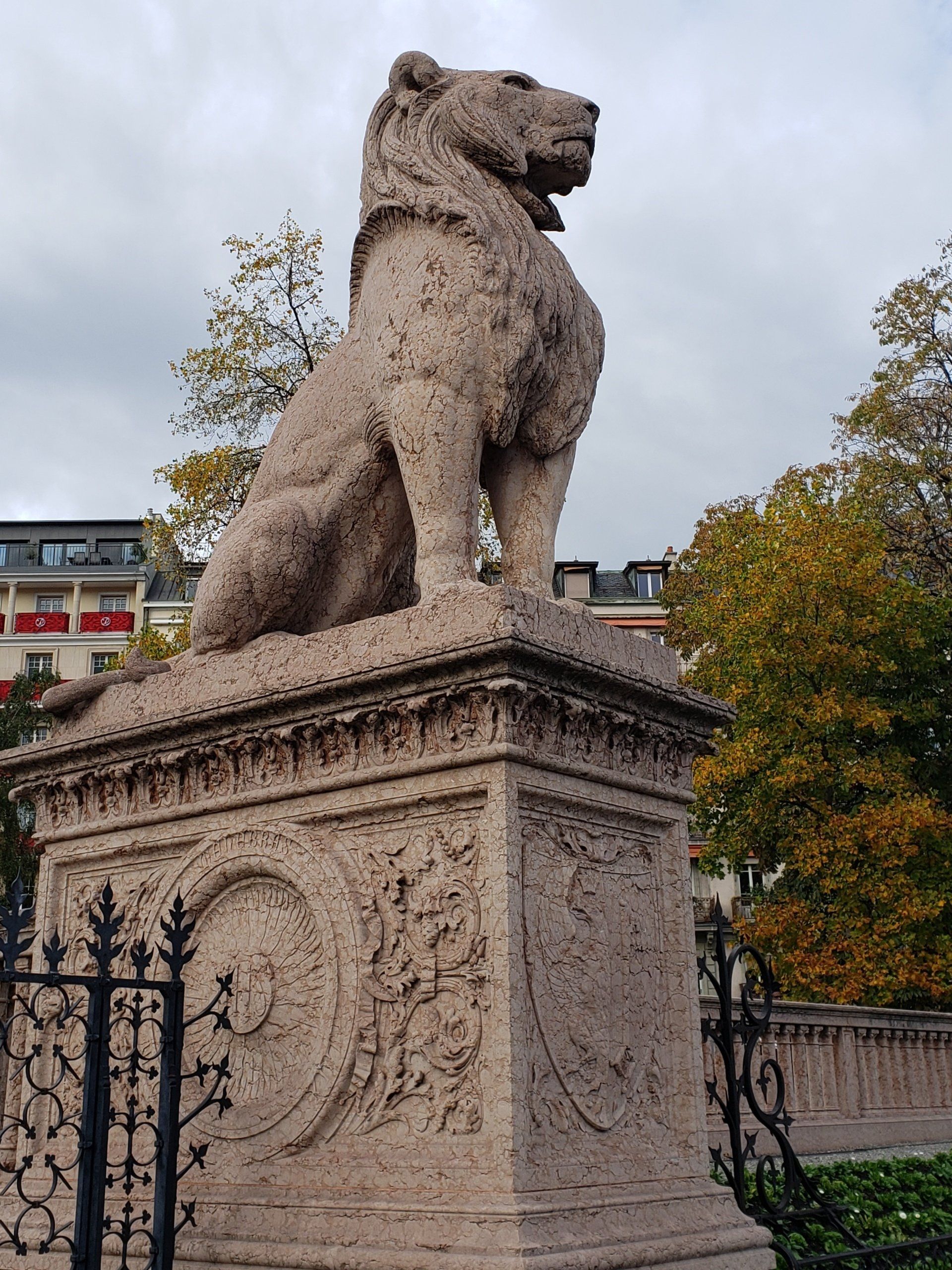 A statue of a lion sitting on top of a stone pedestal