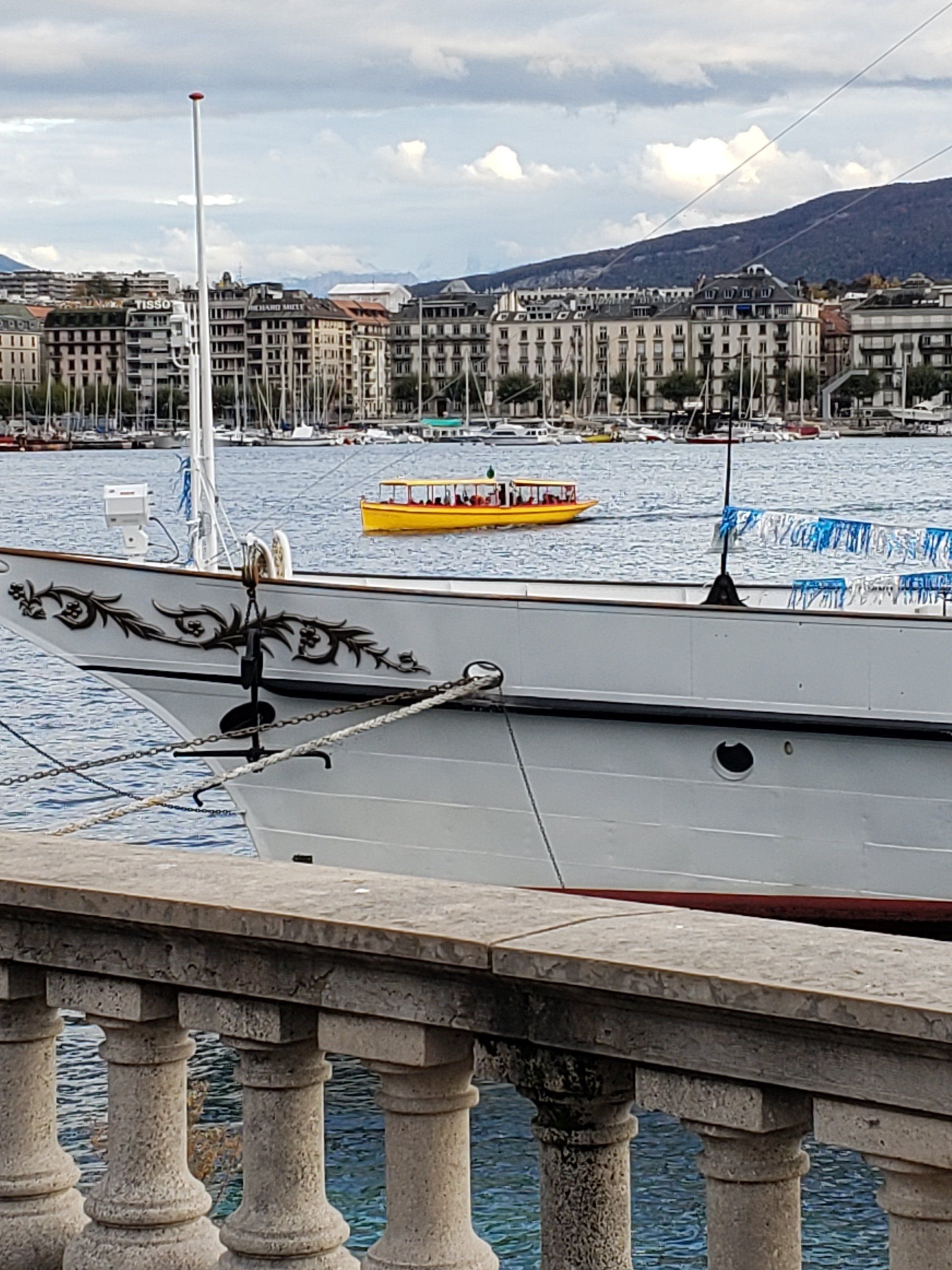 A boat is docked in the water with a yellow boat in the background.