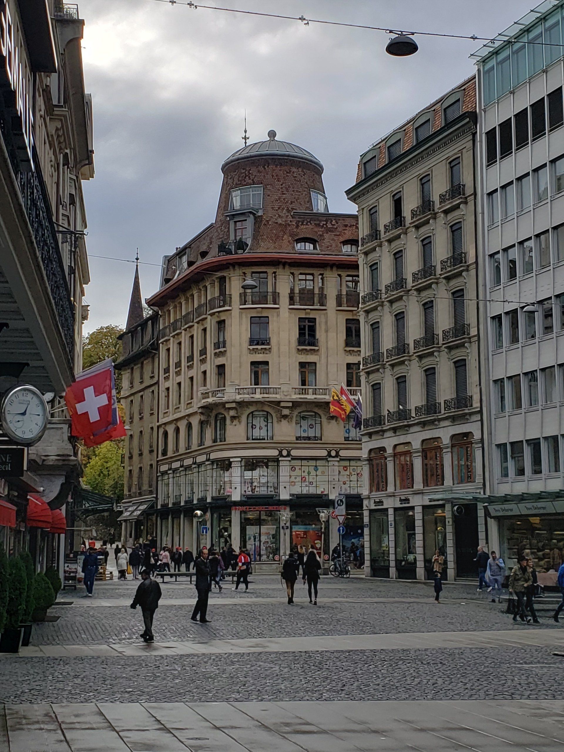 A group of people are walking down a cobblestone street in a city.