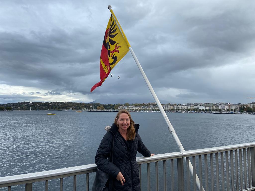 A woman is standing on a bridge with a flag flying in the wind.