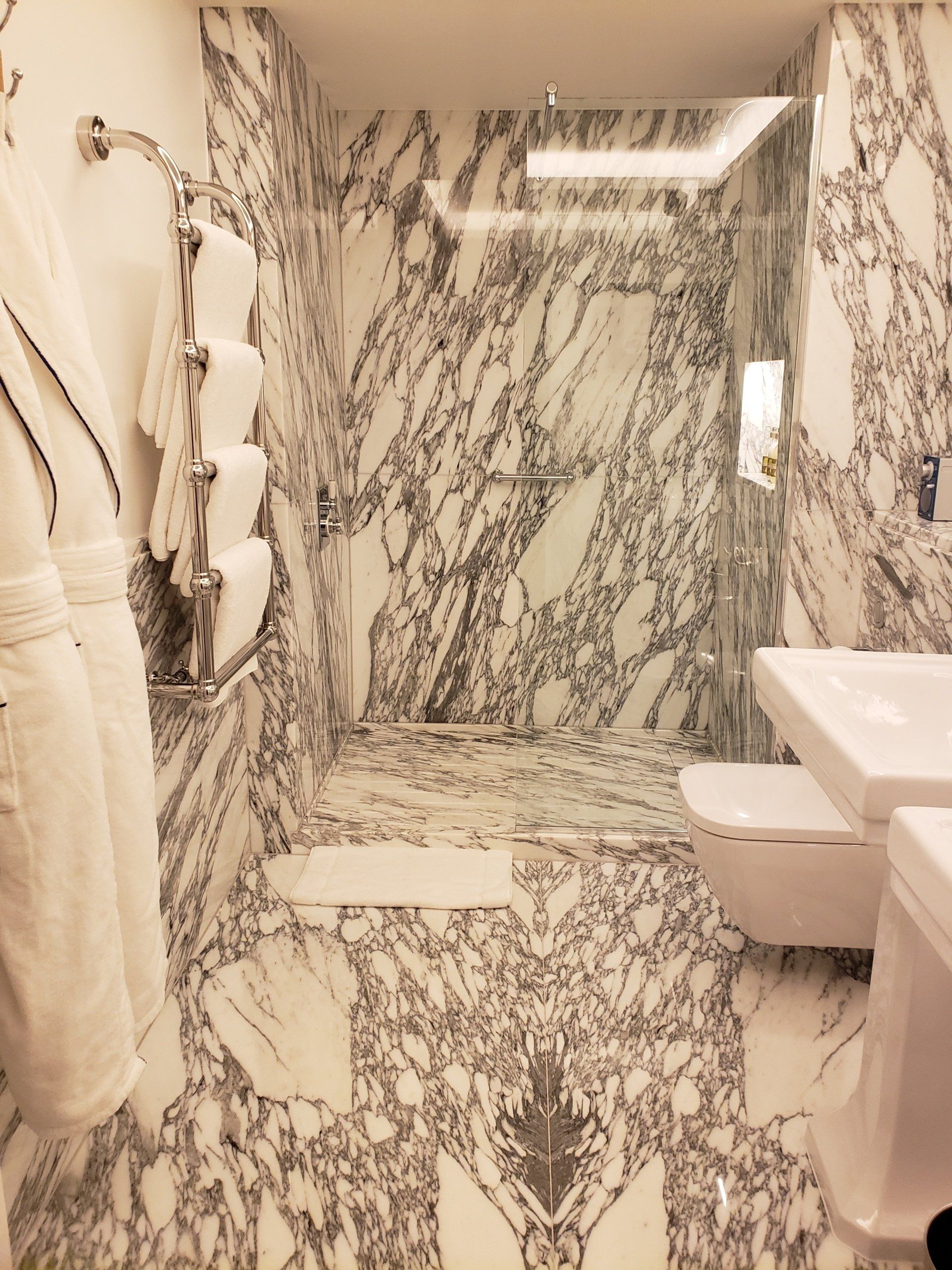 A bathroom with marble walls and a walk in shower