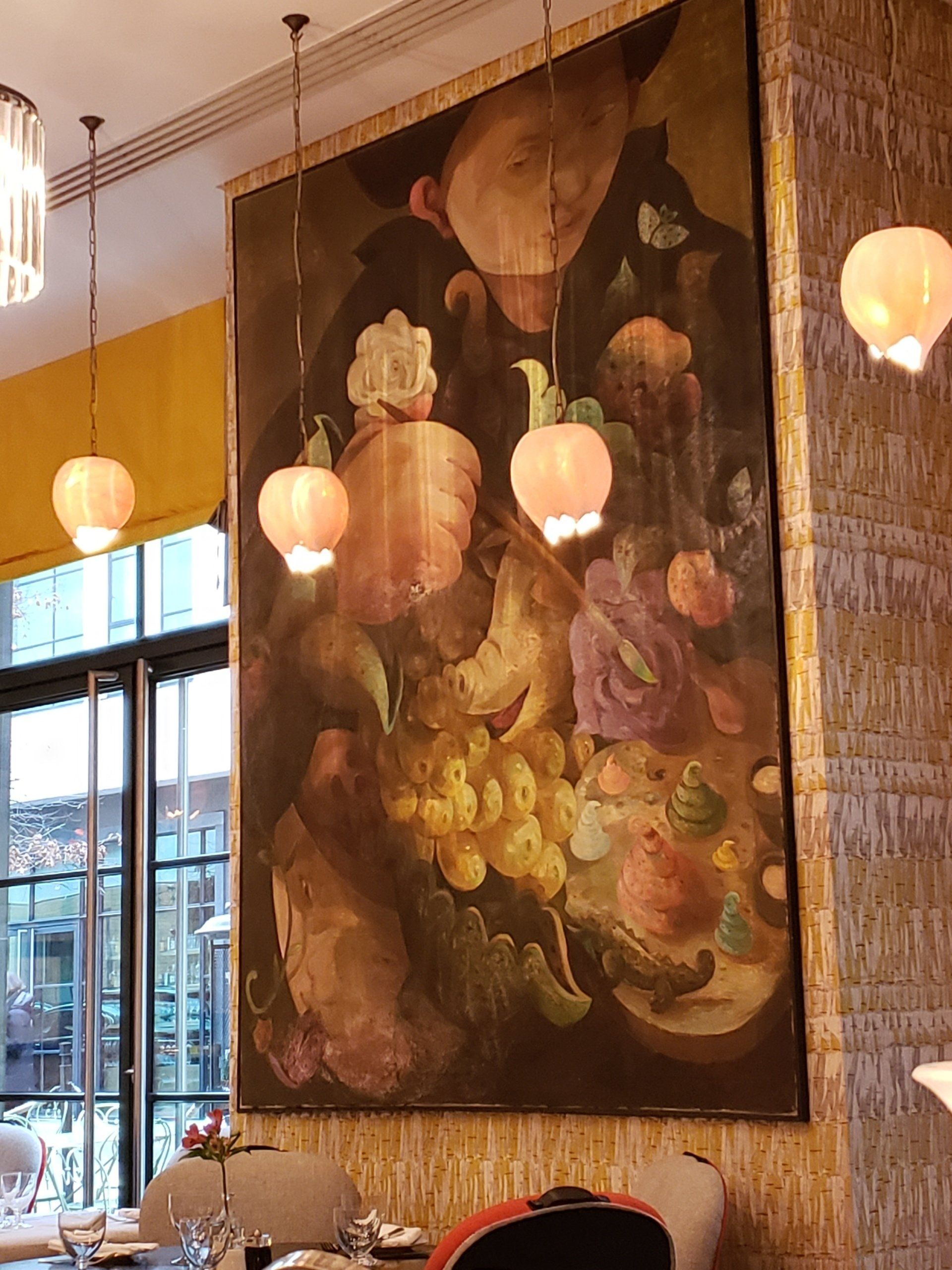 A large painting hangs on a wall in a restaurant