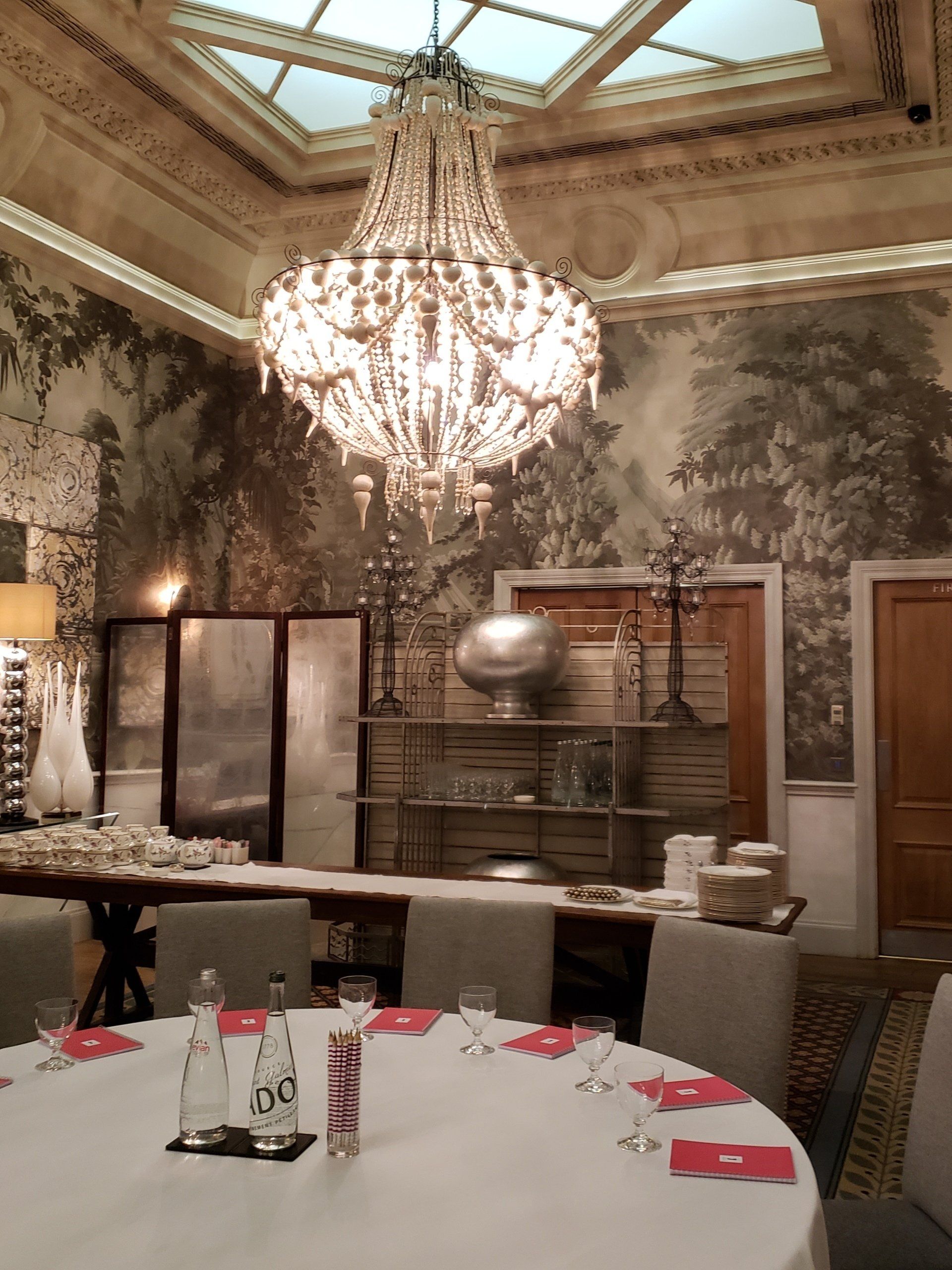 A room with tables and chairs and a chandelier hanging from the ceiling