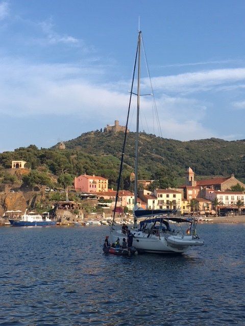 A sailboat is docked in a harbor with a mountain in the background