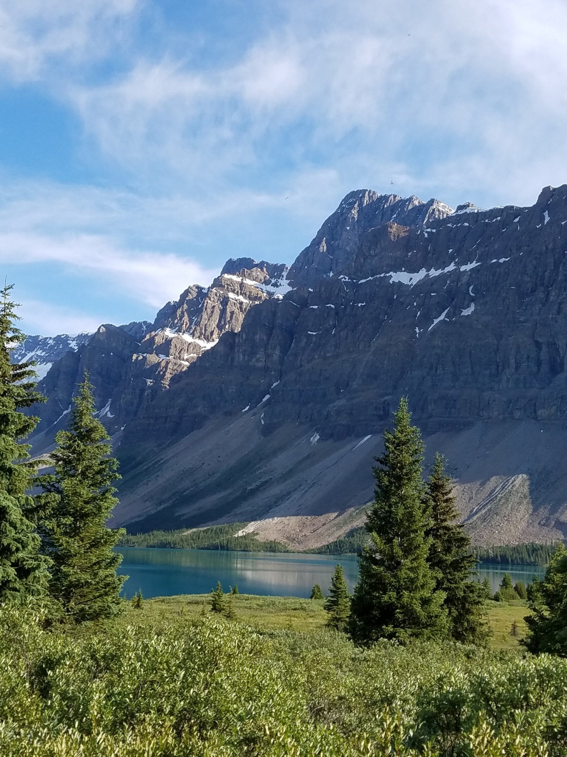 A lake surrounded by mountains and trees on a sunny day