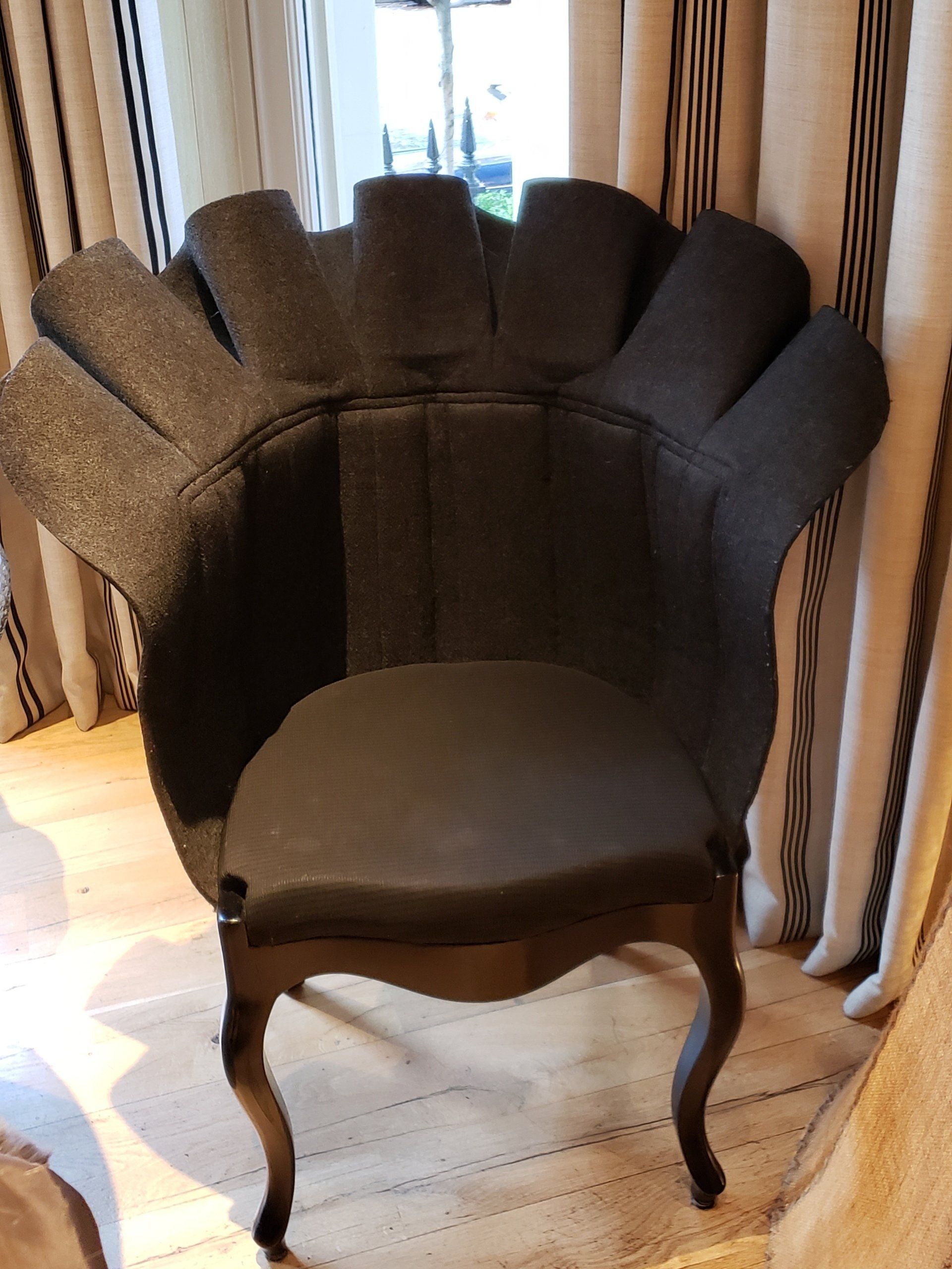 A black chair is sitting in front of a window in a room.