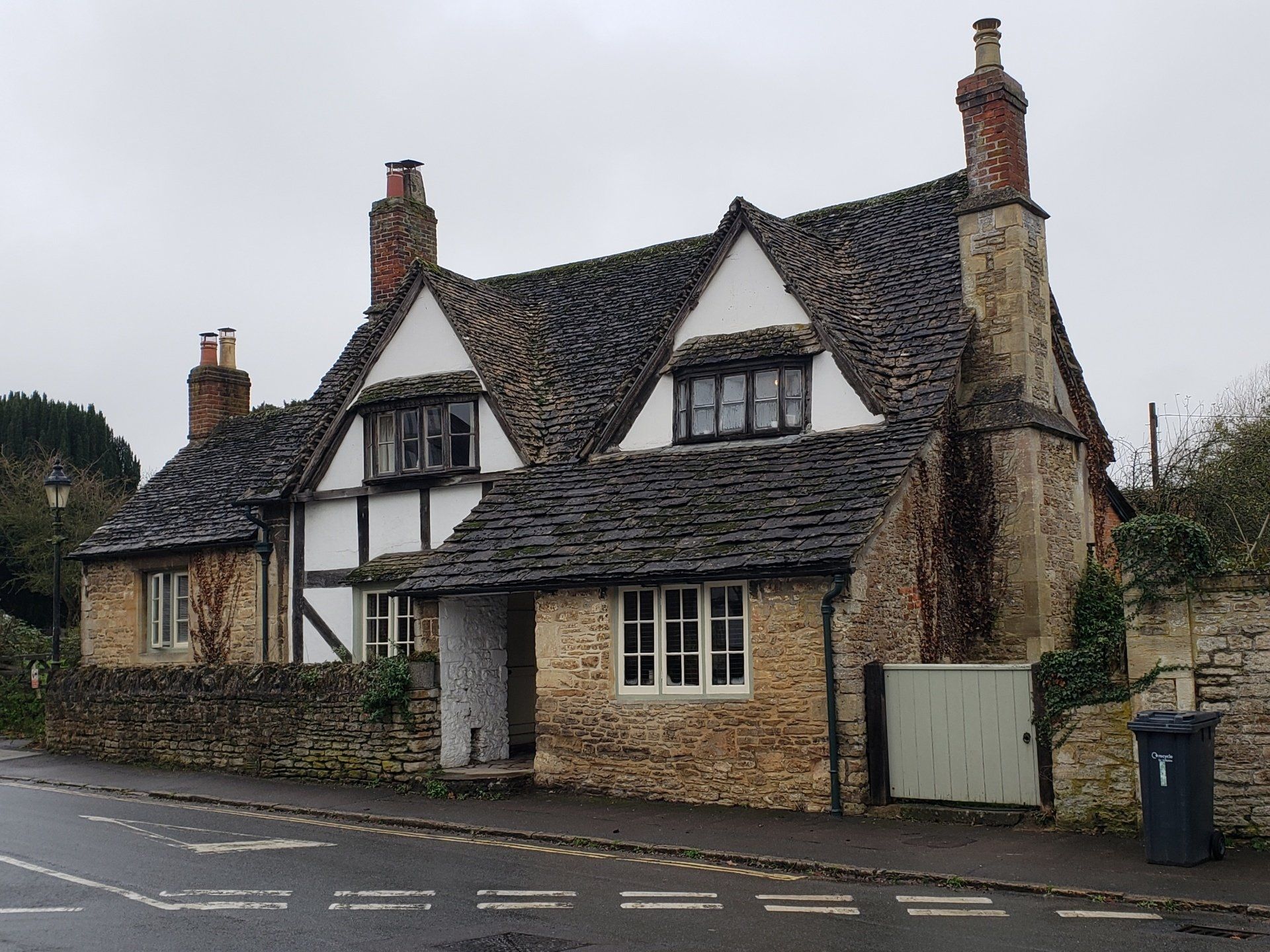 A stone house with a black and white roof and chimneys