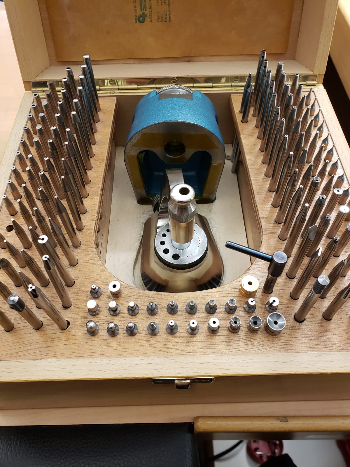 A wooden box filled with a bunch of tools and a machine.