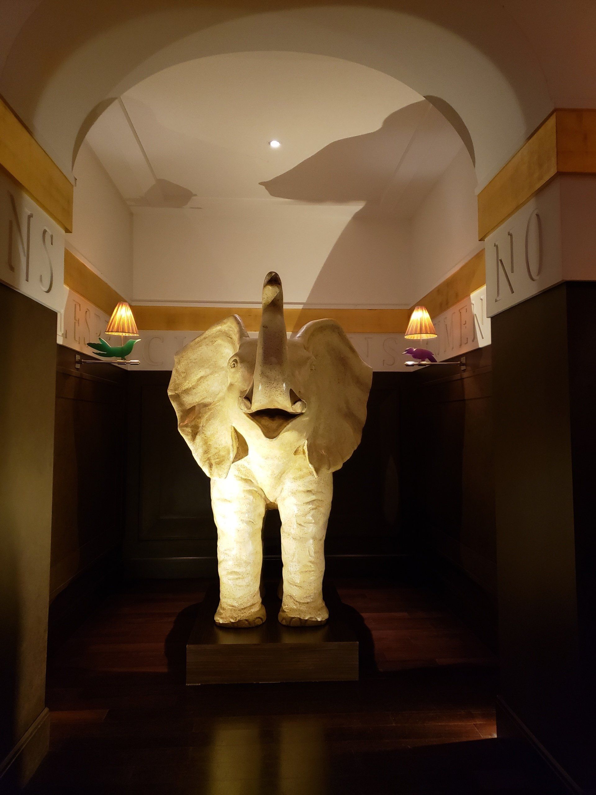 A statue of an elephant is lit up in a dark room