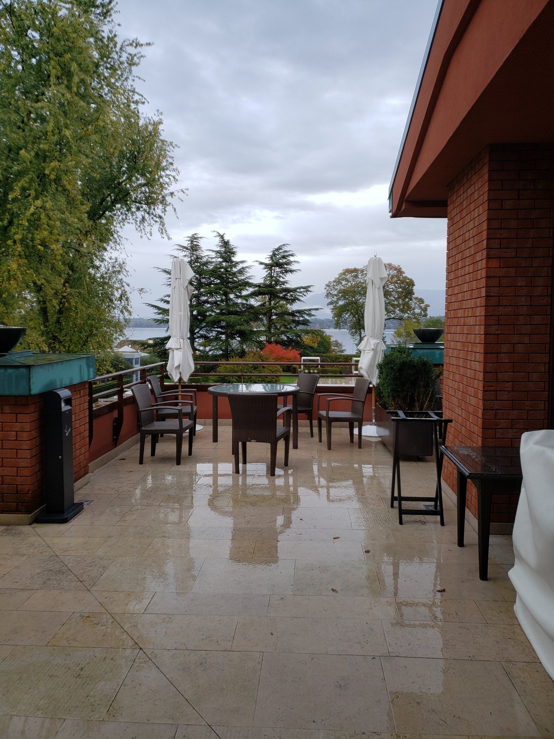 A patio with tables and chairs and umbrellas on a cloudy day