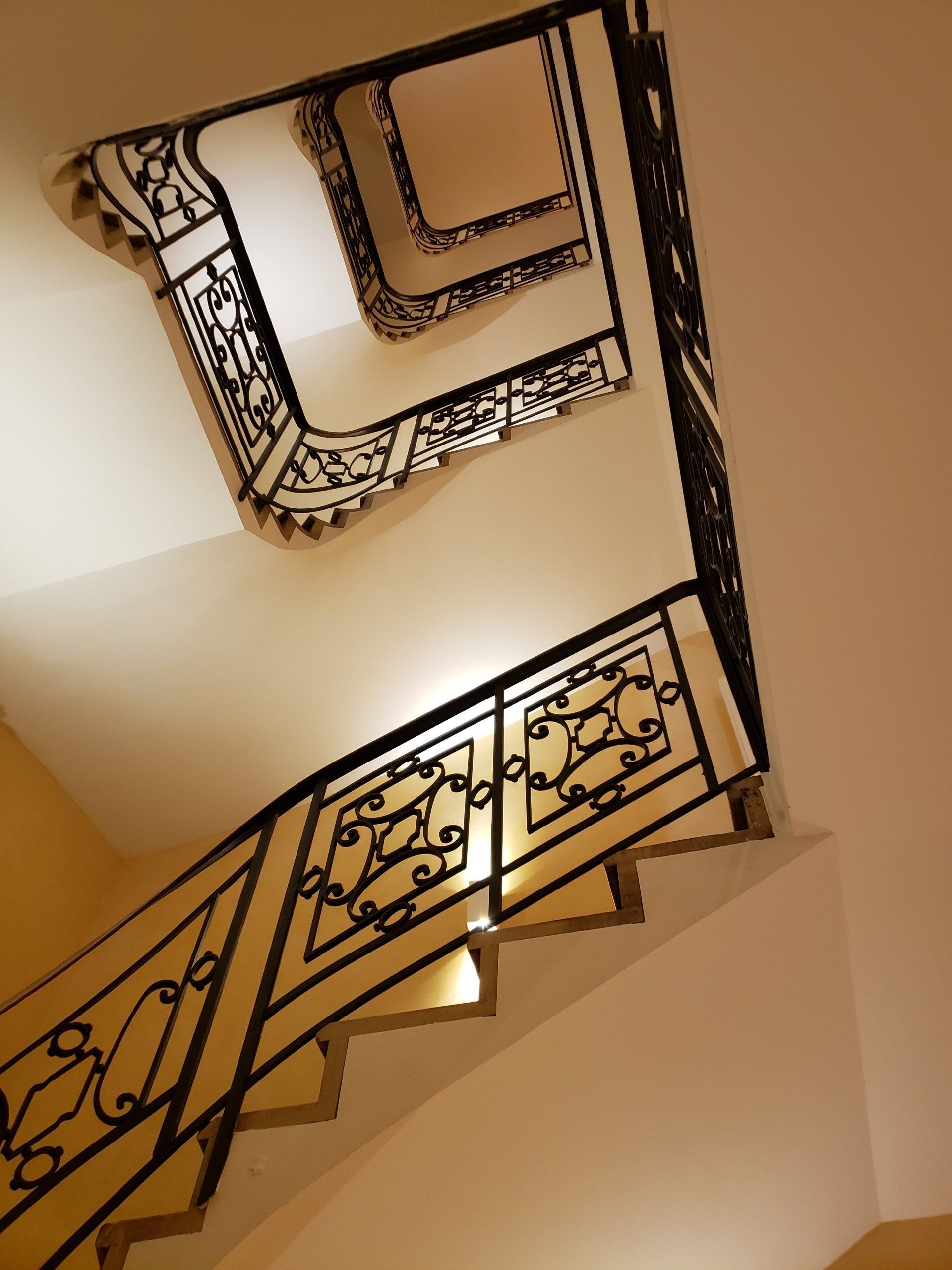 Looking up at a staircase with a wrought iron railing