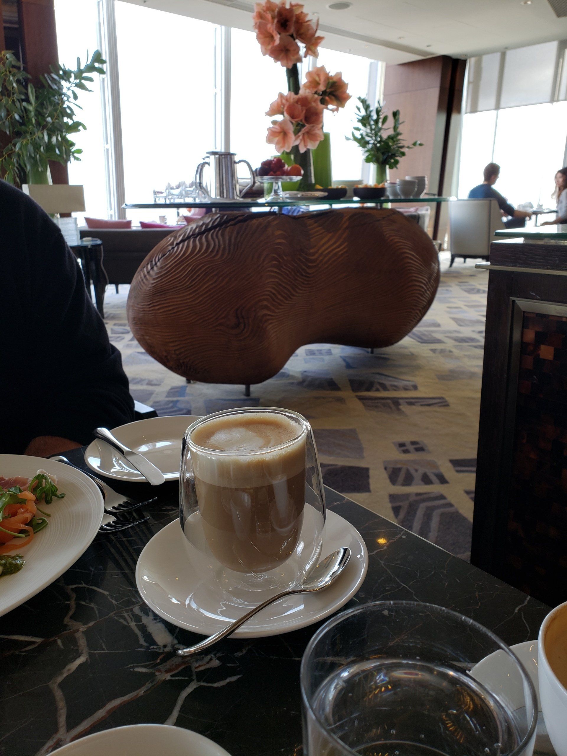 A cup of coffee sits on a saucer on a table