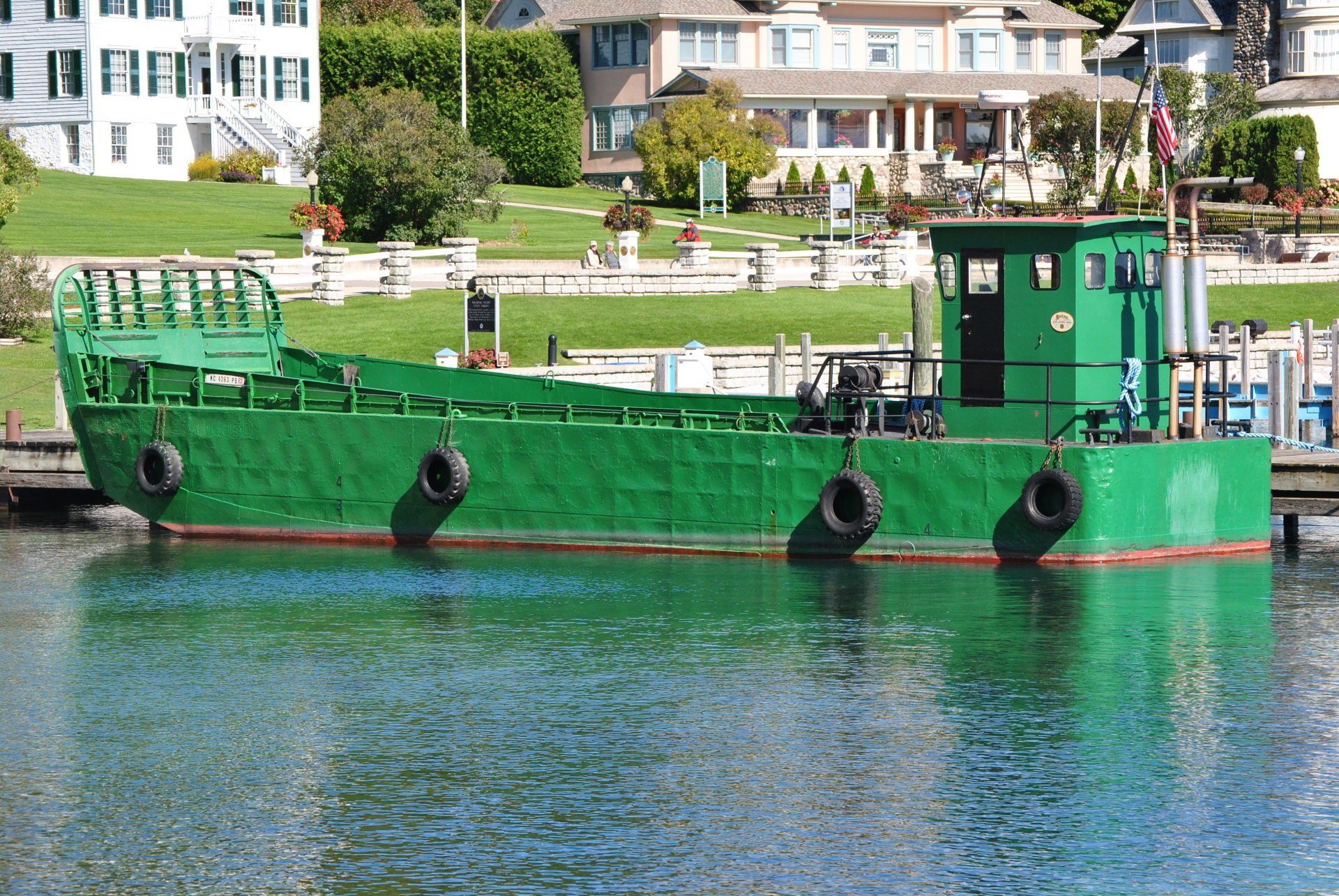 A green boat is docked in a body of water