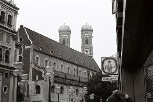 A black and white photo of a city street with a church in the background