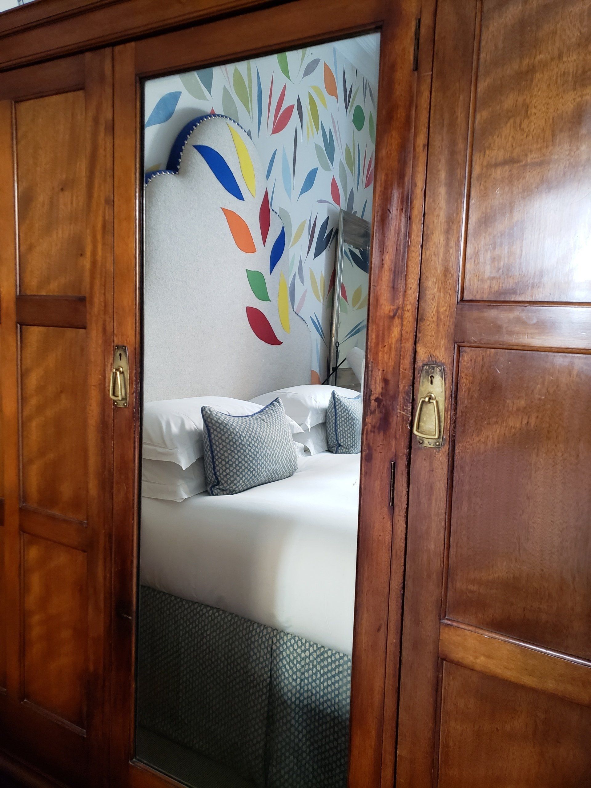 A bedroom with a bed and a mirror behind it