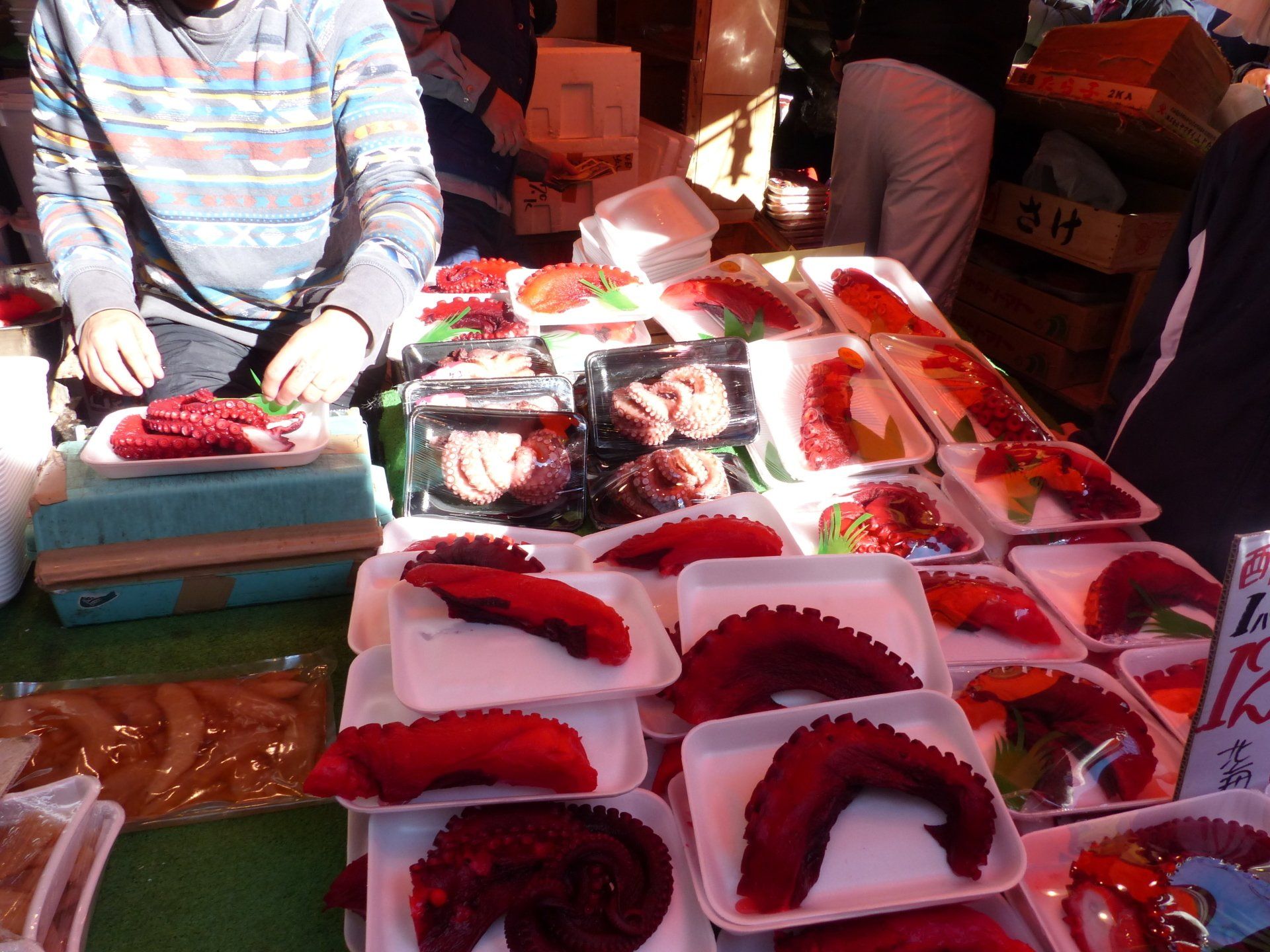 A table full of trays of food including octopus