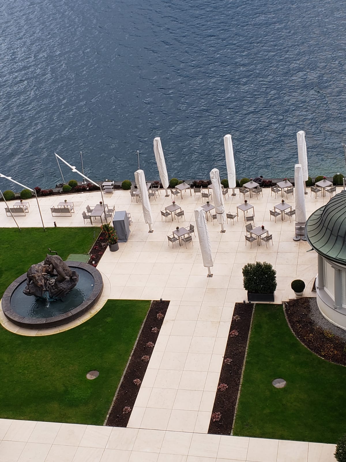 An aerial view of a patio with tables and umbrellas overlooking a body of water