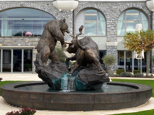 A statue of a bear fighting a bull in a fountain in front of a building.