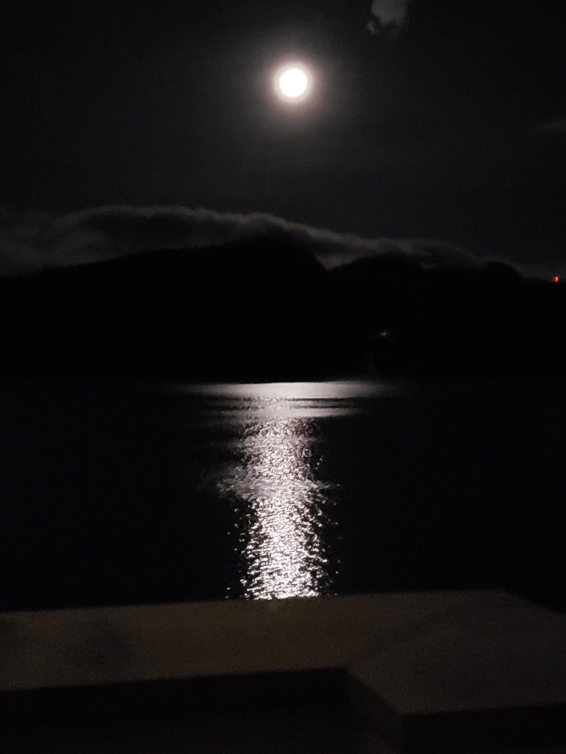 A full moon shines over a body of water