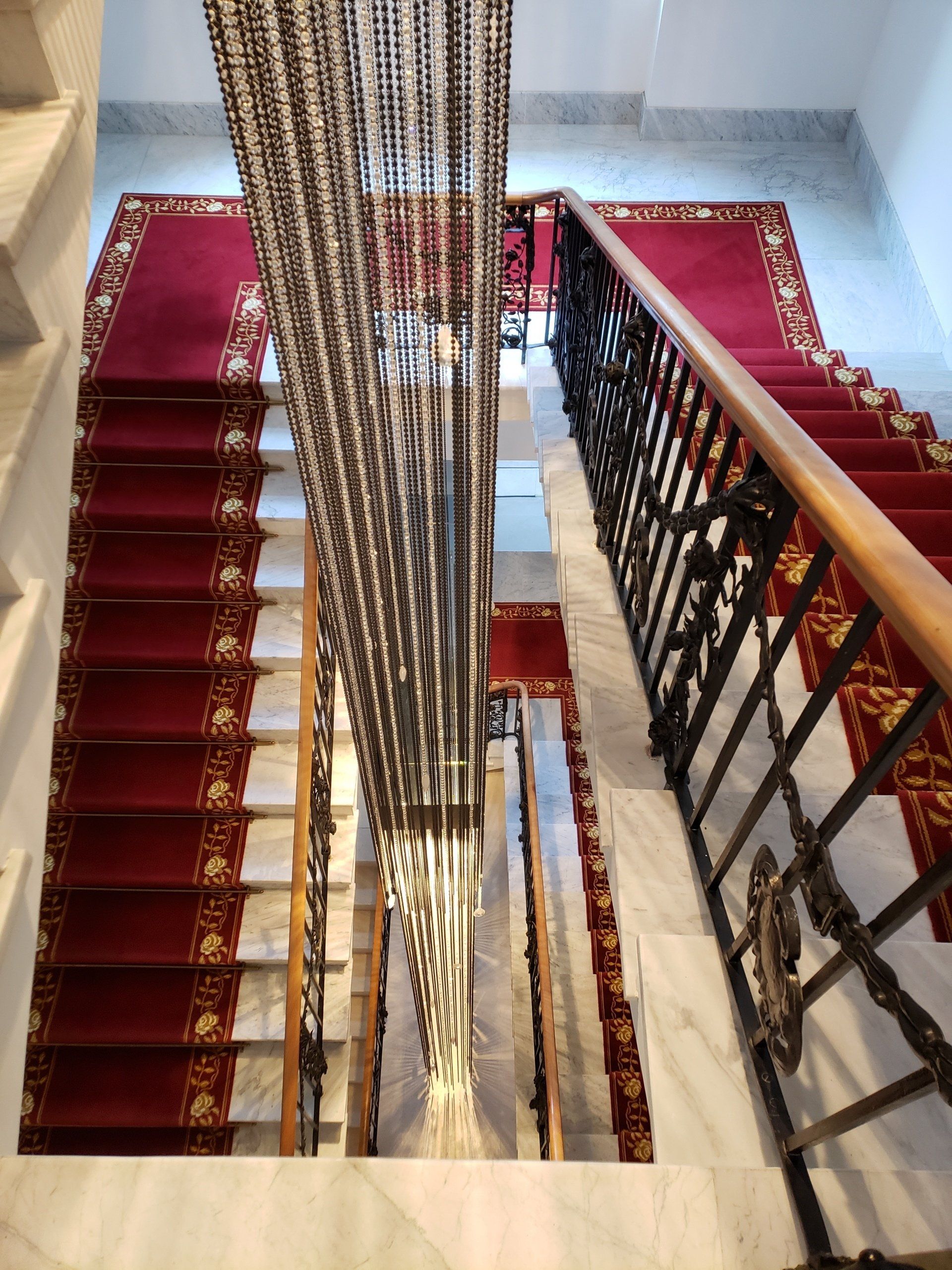 A staircase with a red carpet and a black railing