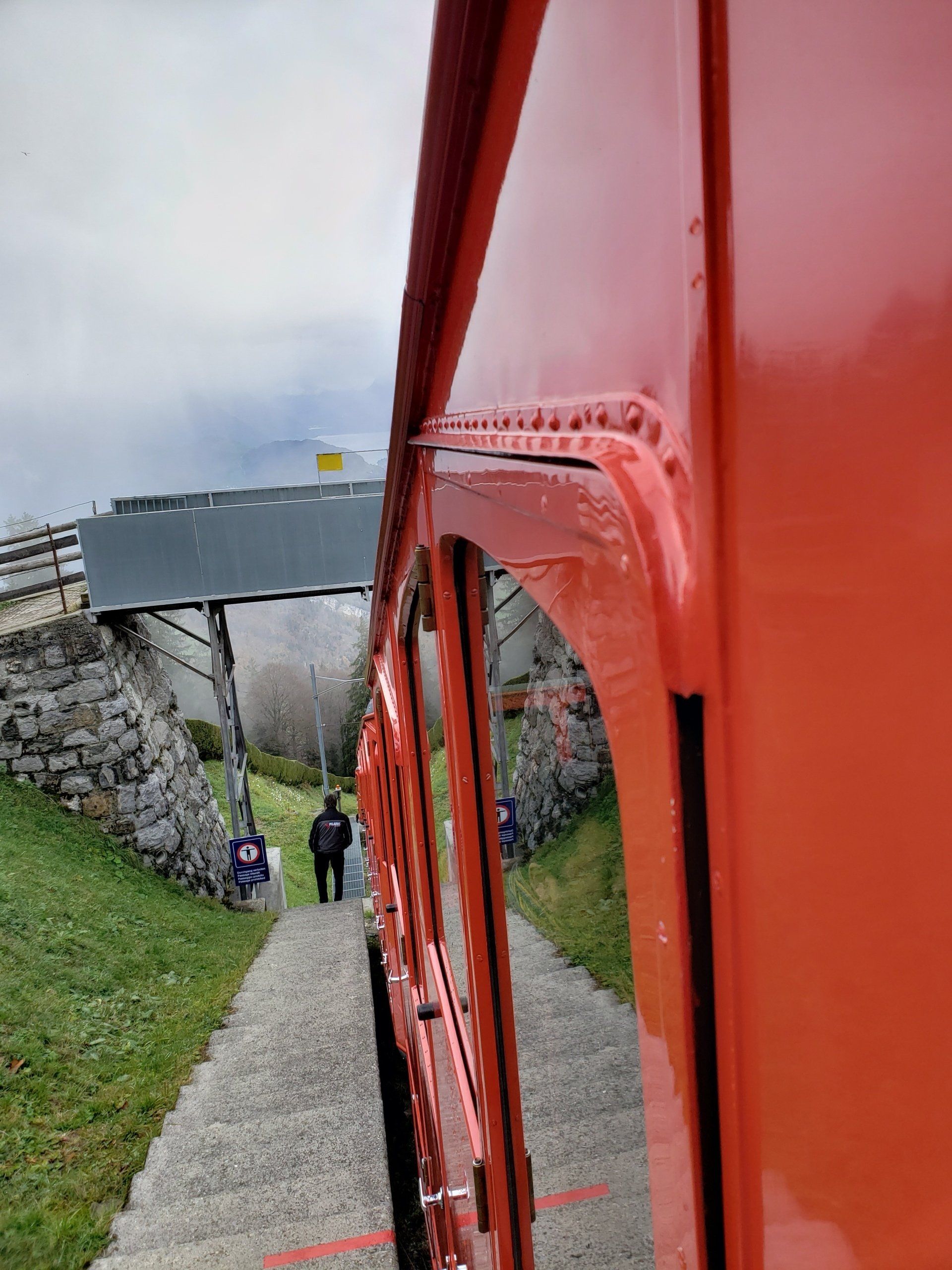 A person is walking down a path next to a red bus.