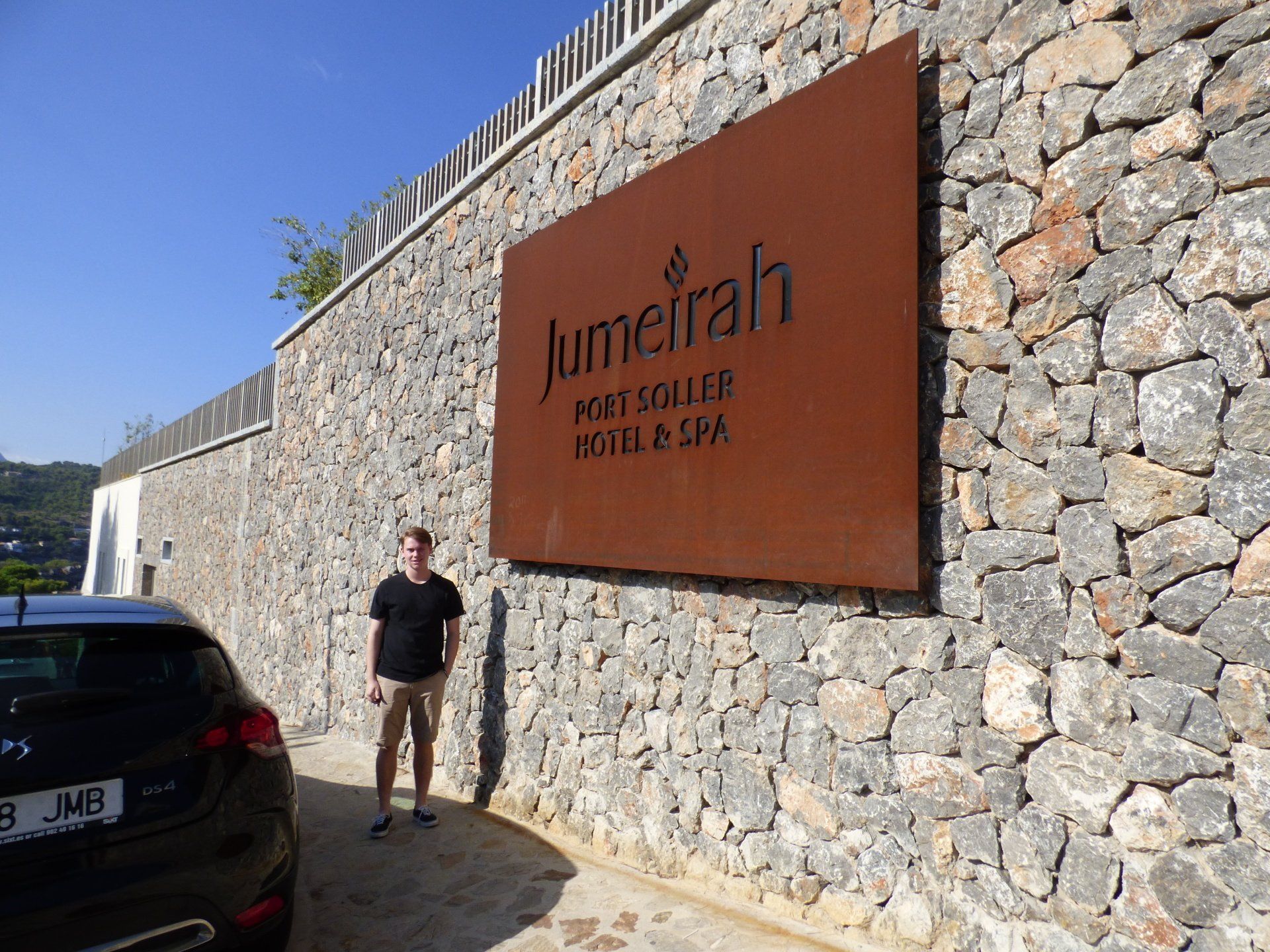 A man standing in front of a stone wall with a sign that says jumeirah