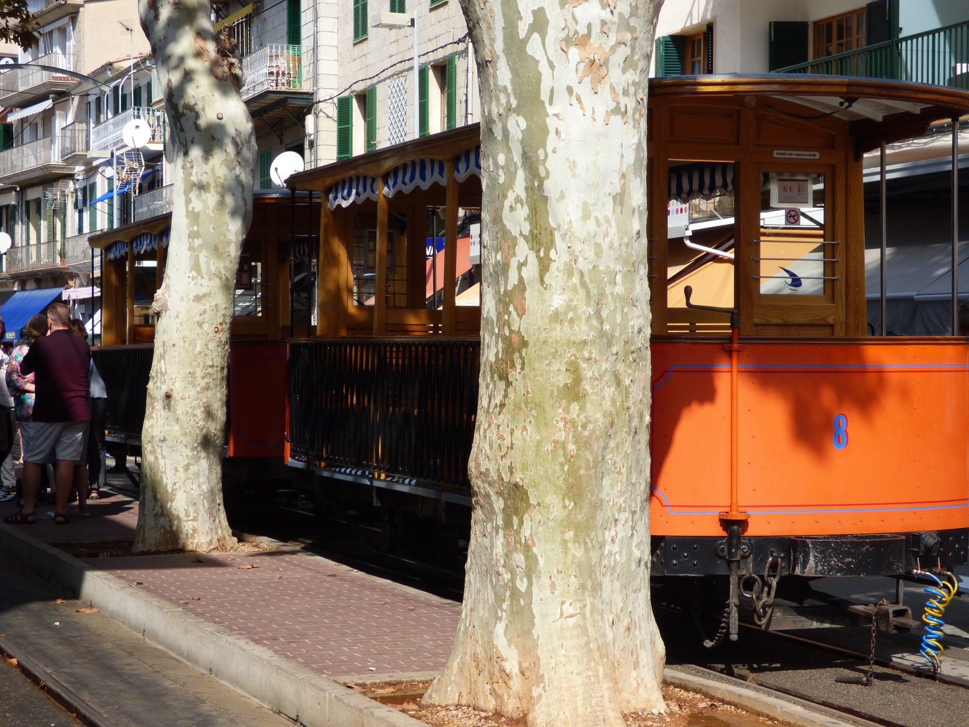 A red train is parked on the tracks next to trees