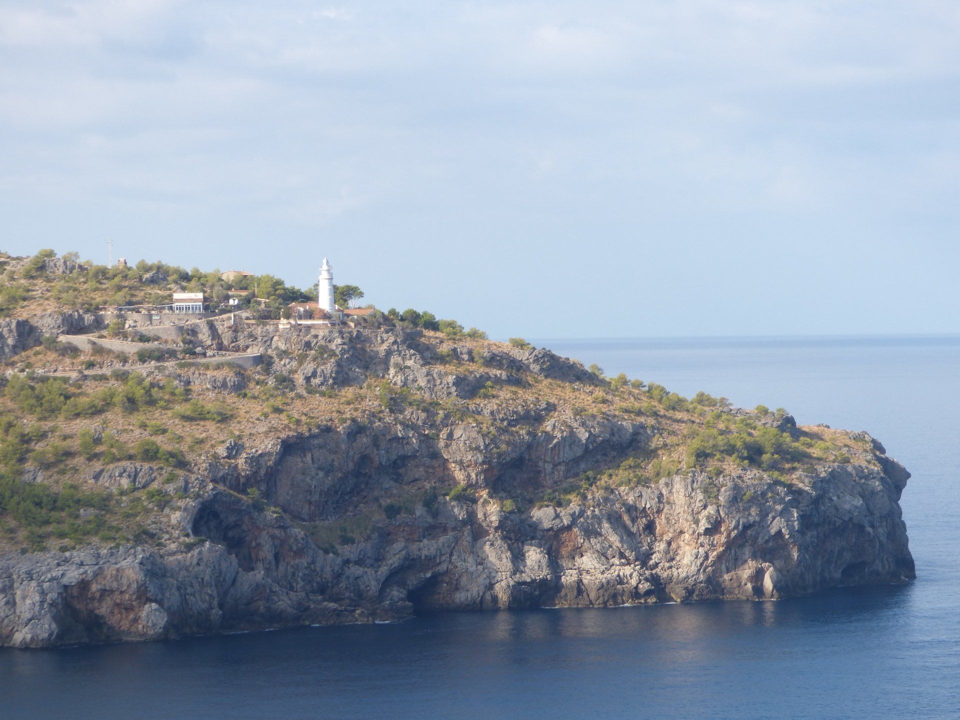 A small island in the middle of the ocean with a lighthouse on top of it