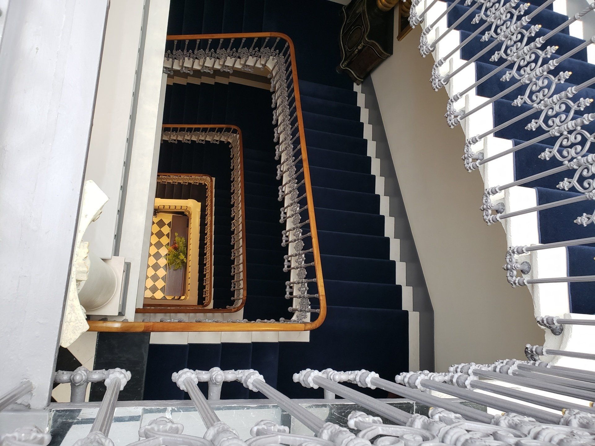 A spiral staircase with a blue carpet and white railing