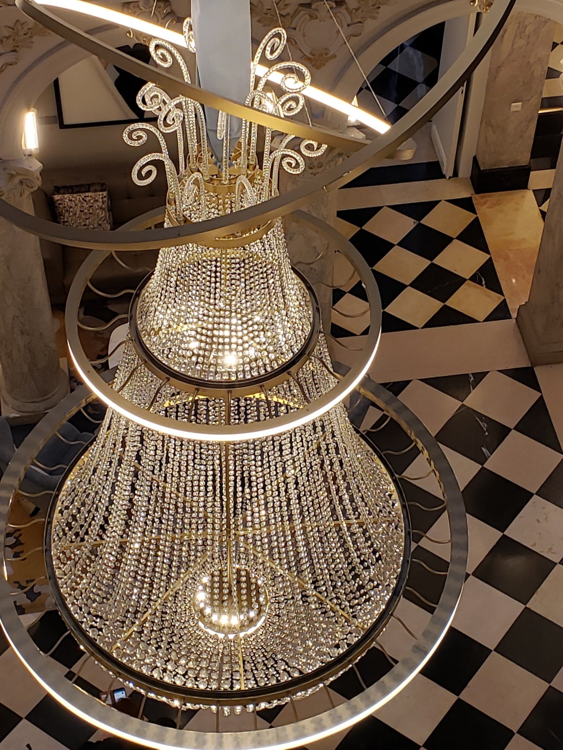 A large chandelier is hanging from the ceiling in a room with a checkered floor