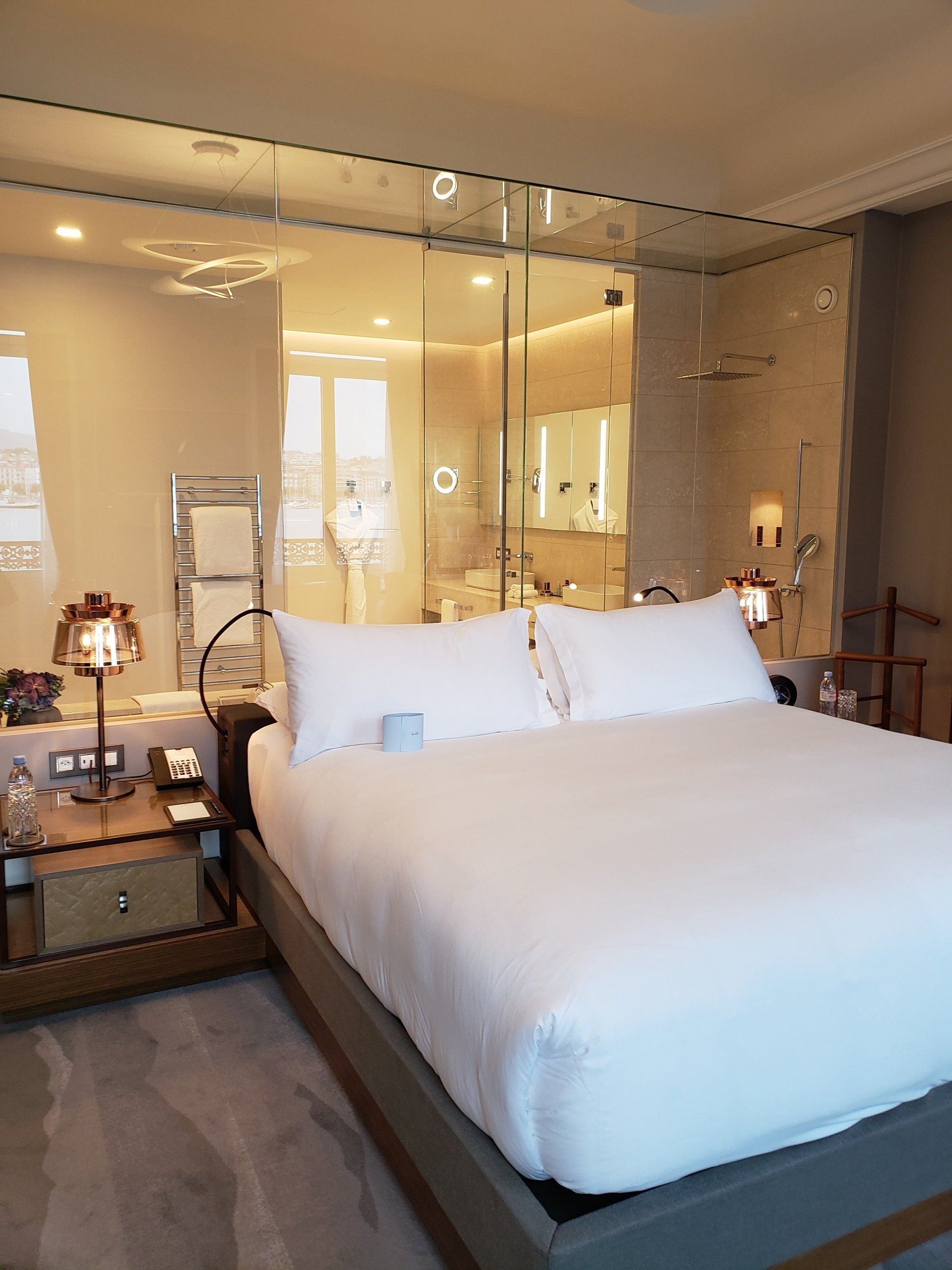 A hotel room with a king size bed and a bathroom behind it.