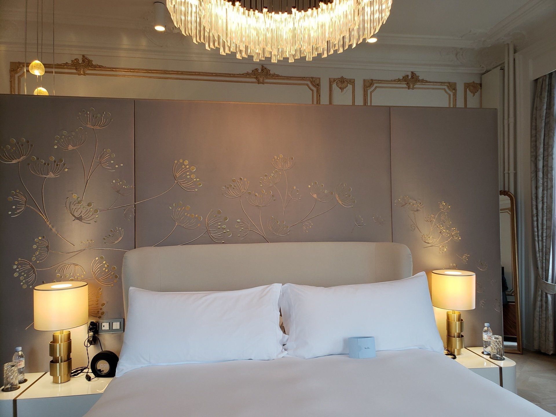 A bedroom with a large bed and a chandelier