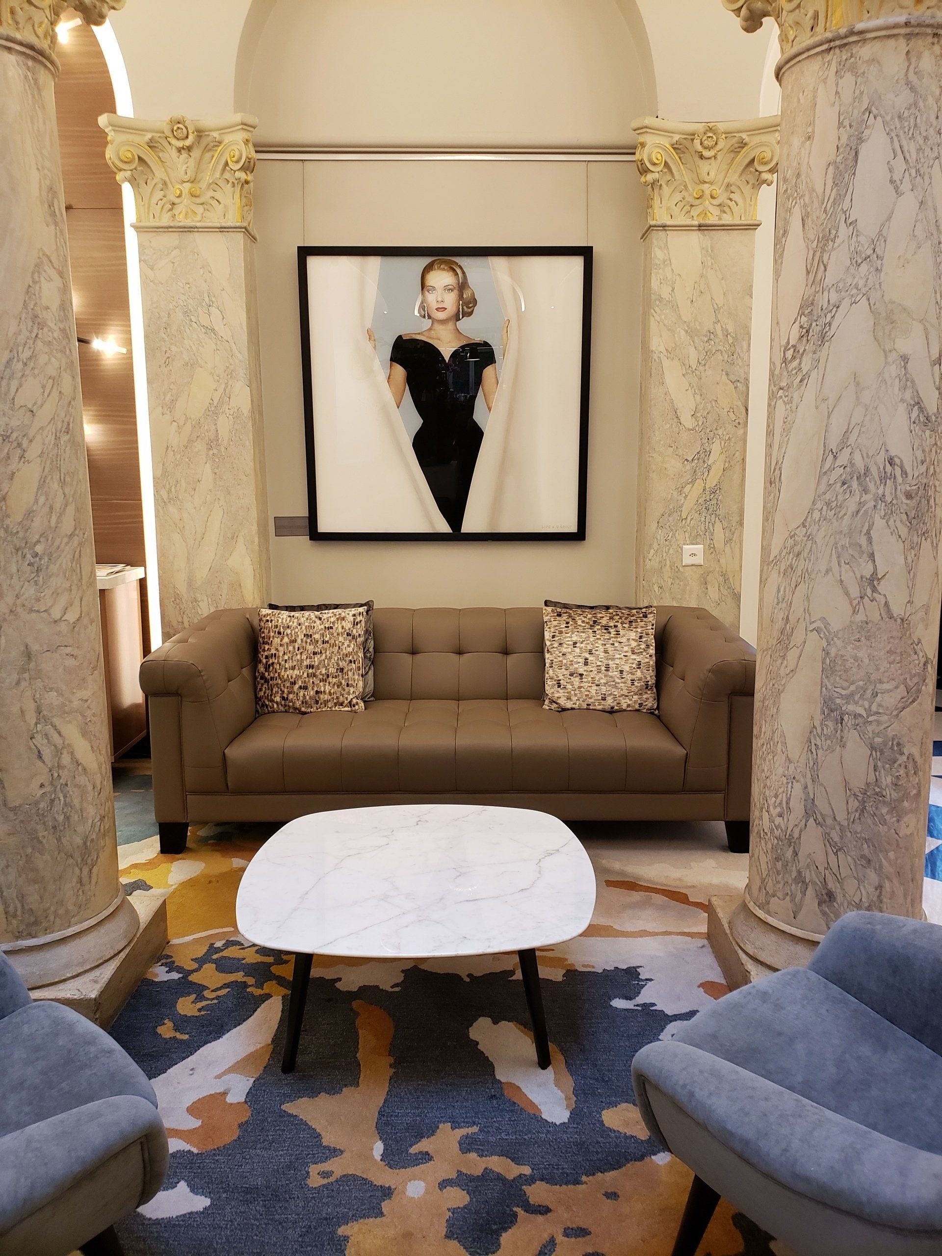 A living room with a couch and chairs and a painting on the wall