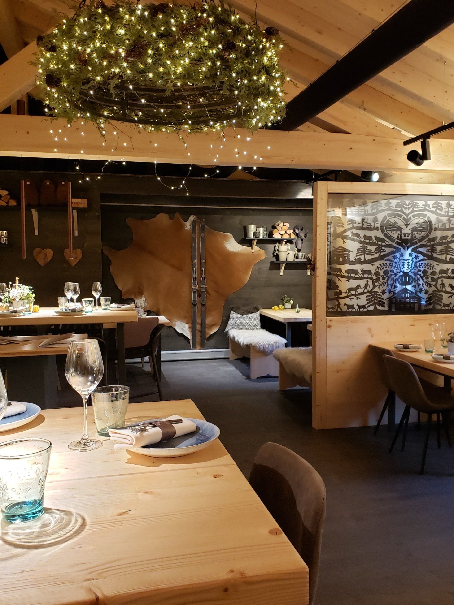 A restaurant with tables and chairs and a wreath on the ceiling