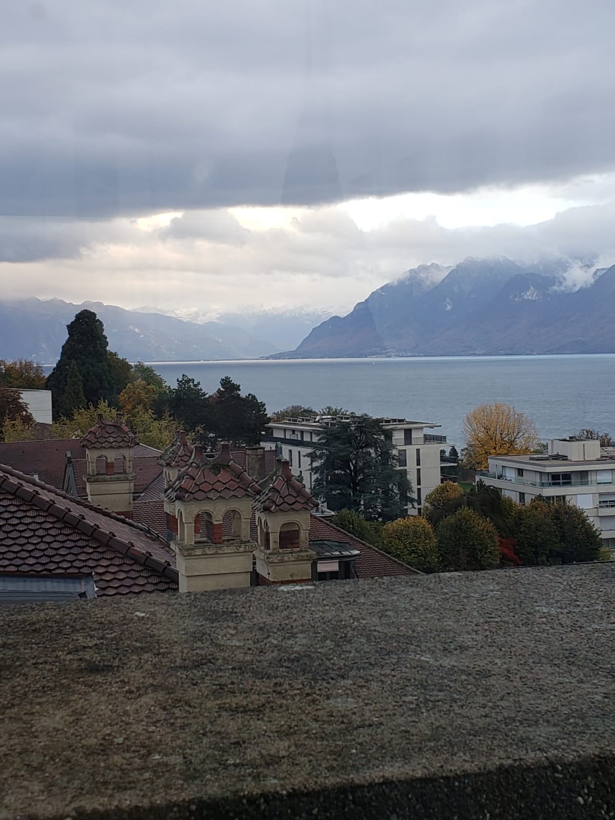 A view of a city with mountains in the background and a body of water in the foreground