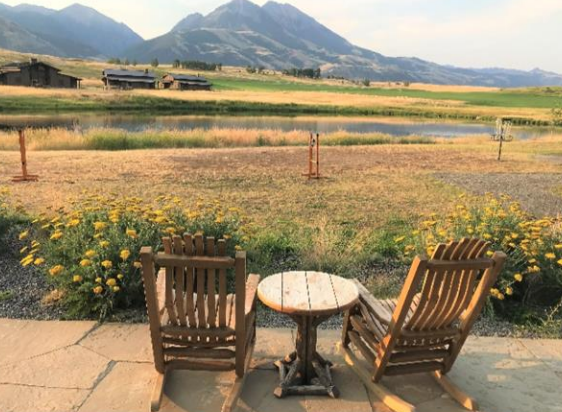 Two rocking chairs and a table on a patio with mountains in the background.