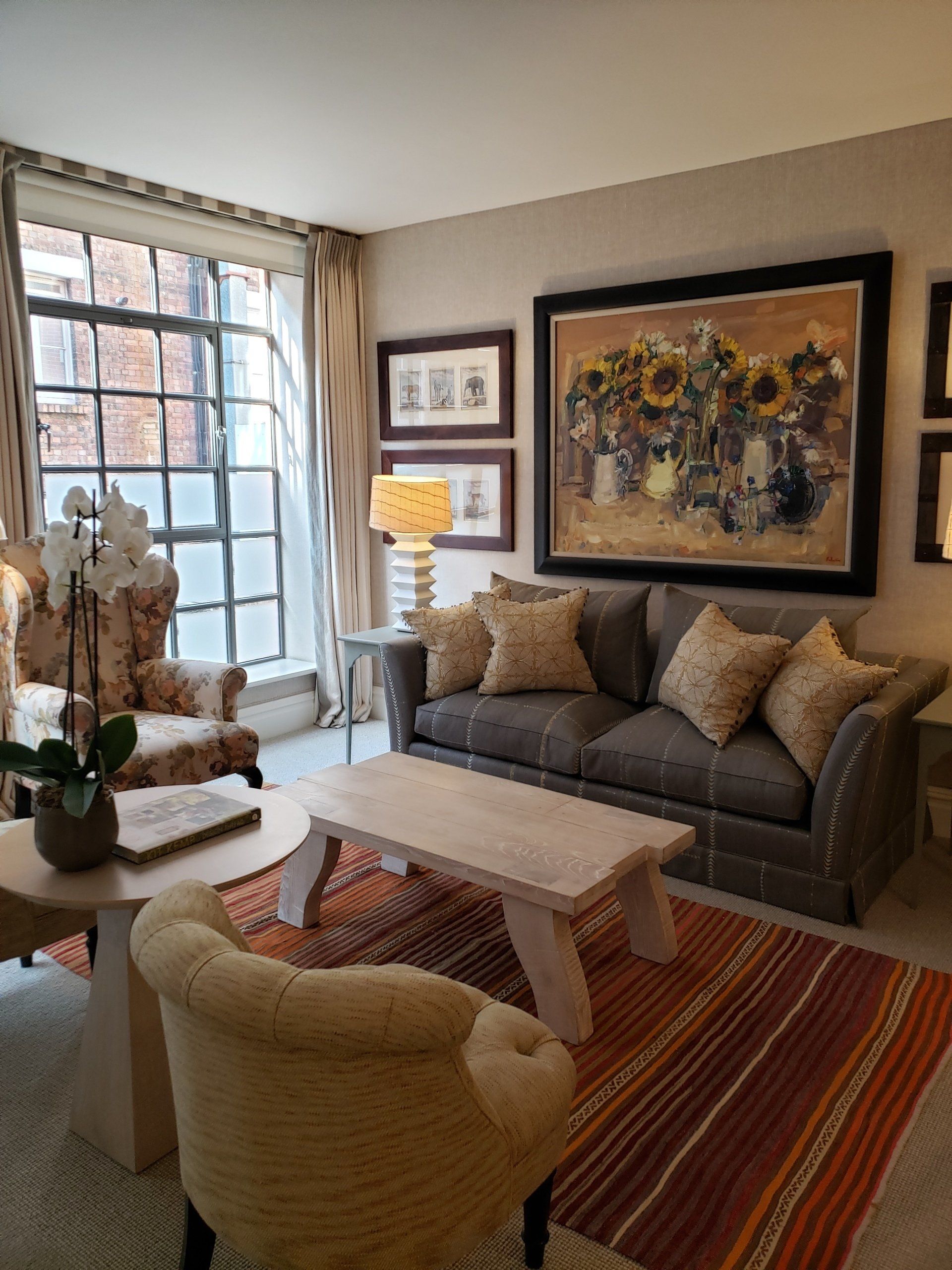 A living room with a couch , chairs , coffee table and a painting on the wall