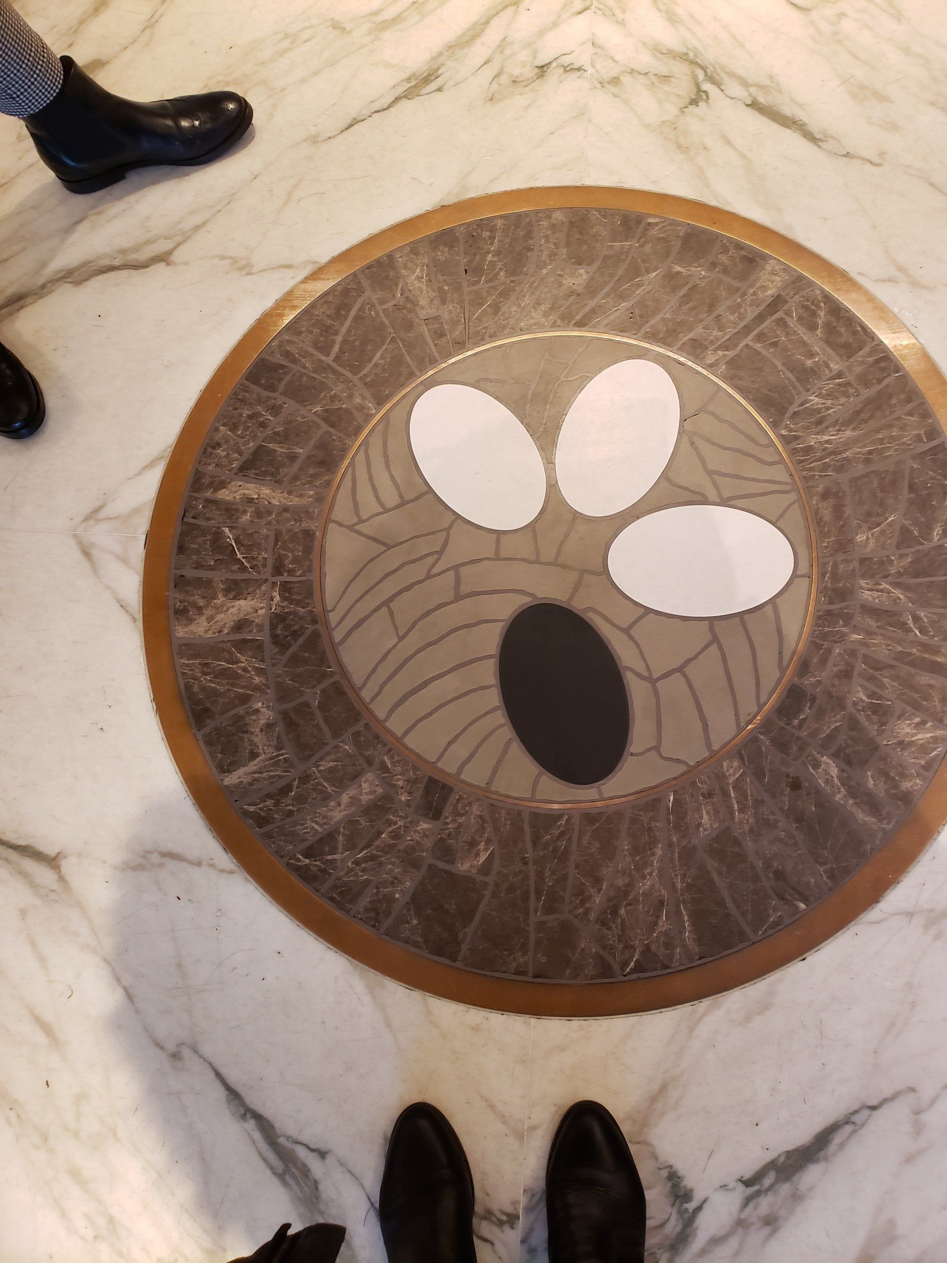 A person standing in front of a marble floor with a circular design on it