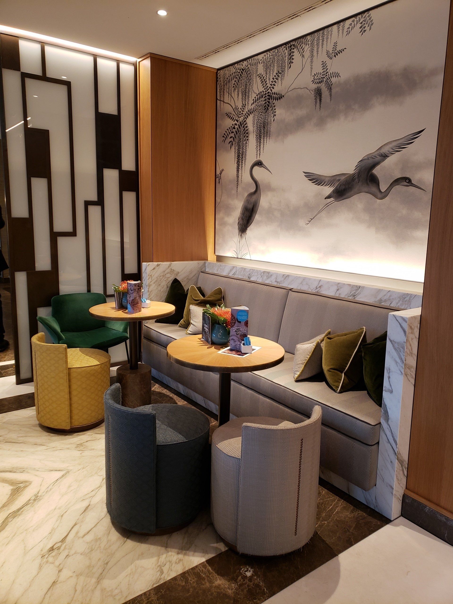 A living room with a couch , chairs , tables and a painting on the wall.