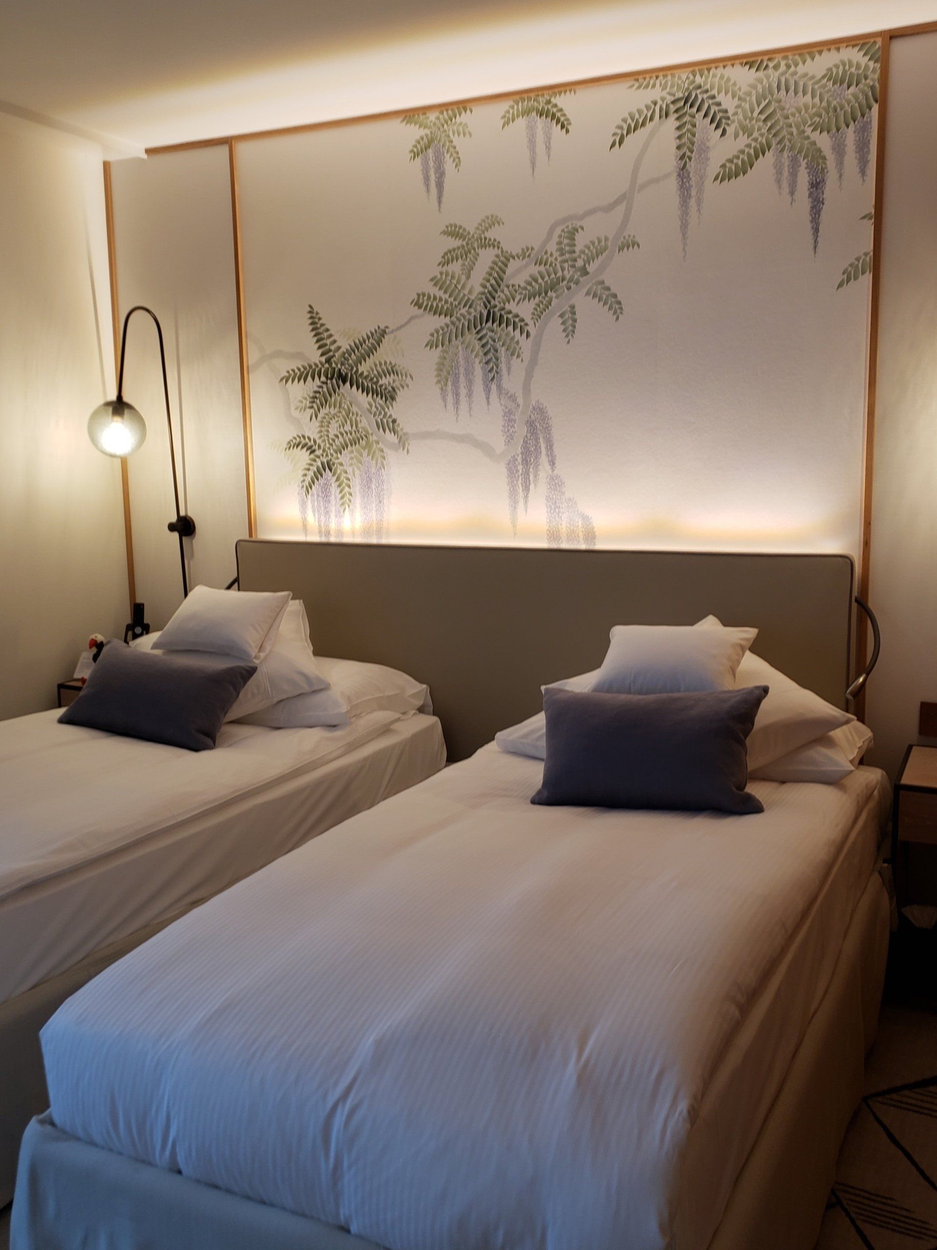 A hotel room with two beds and a painting on the wall.